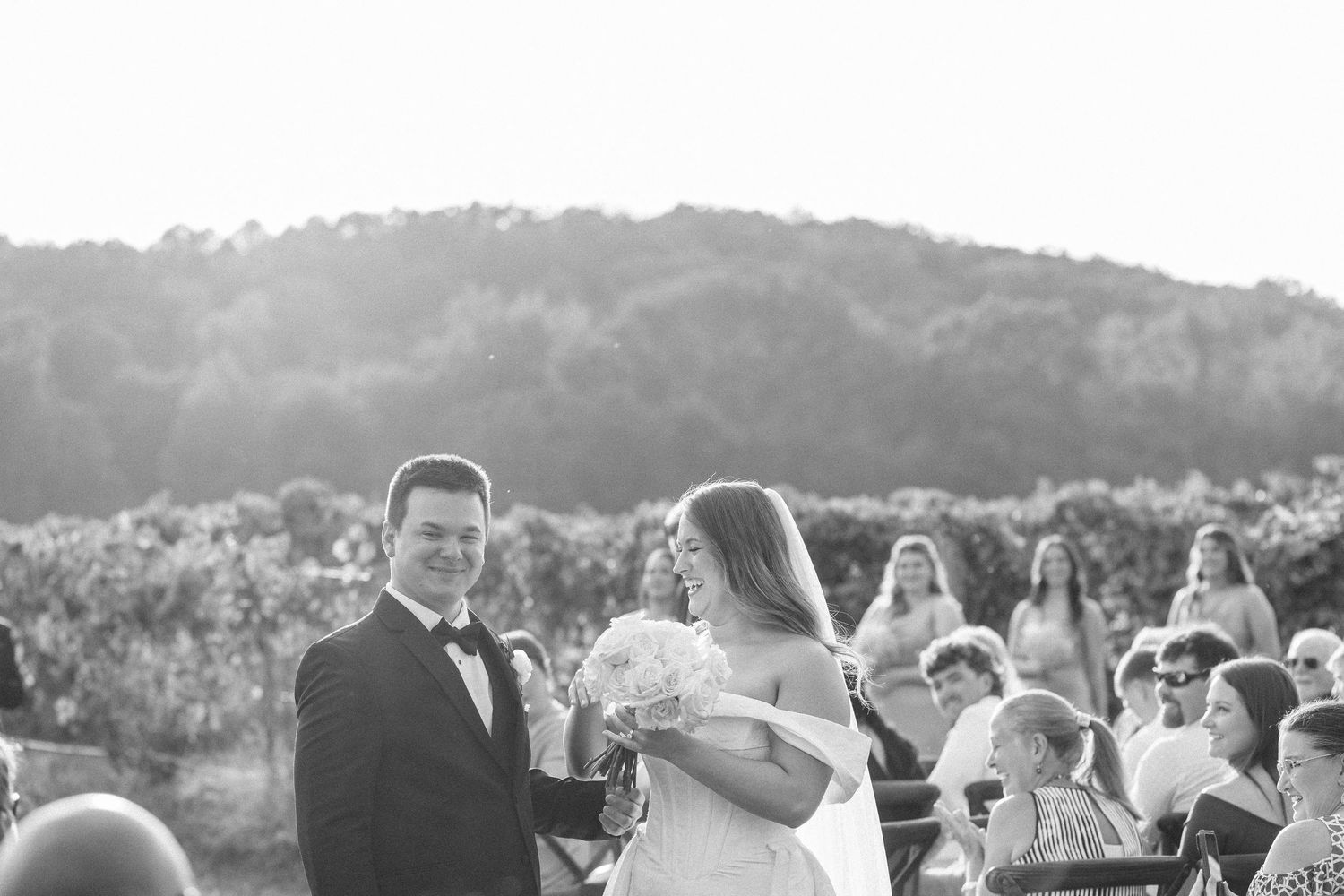 Wedding guests gather outdoors at a scenic mountain venue during a beautiful sunset celebration.