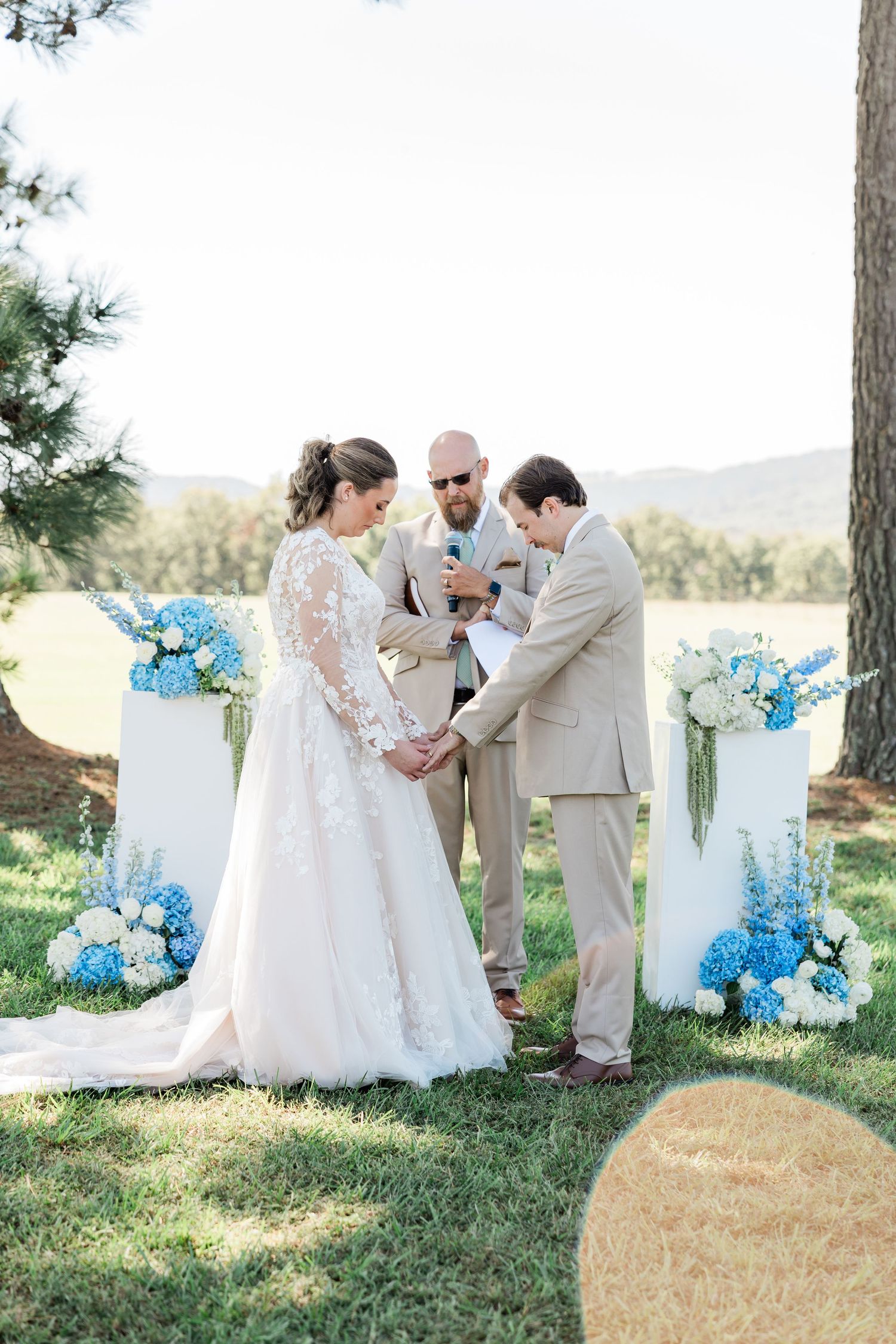 Outdoor wedding ceremony with blue floral arrangements and white decorative elements.