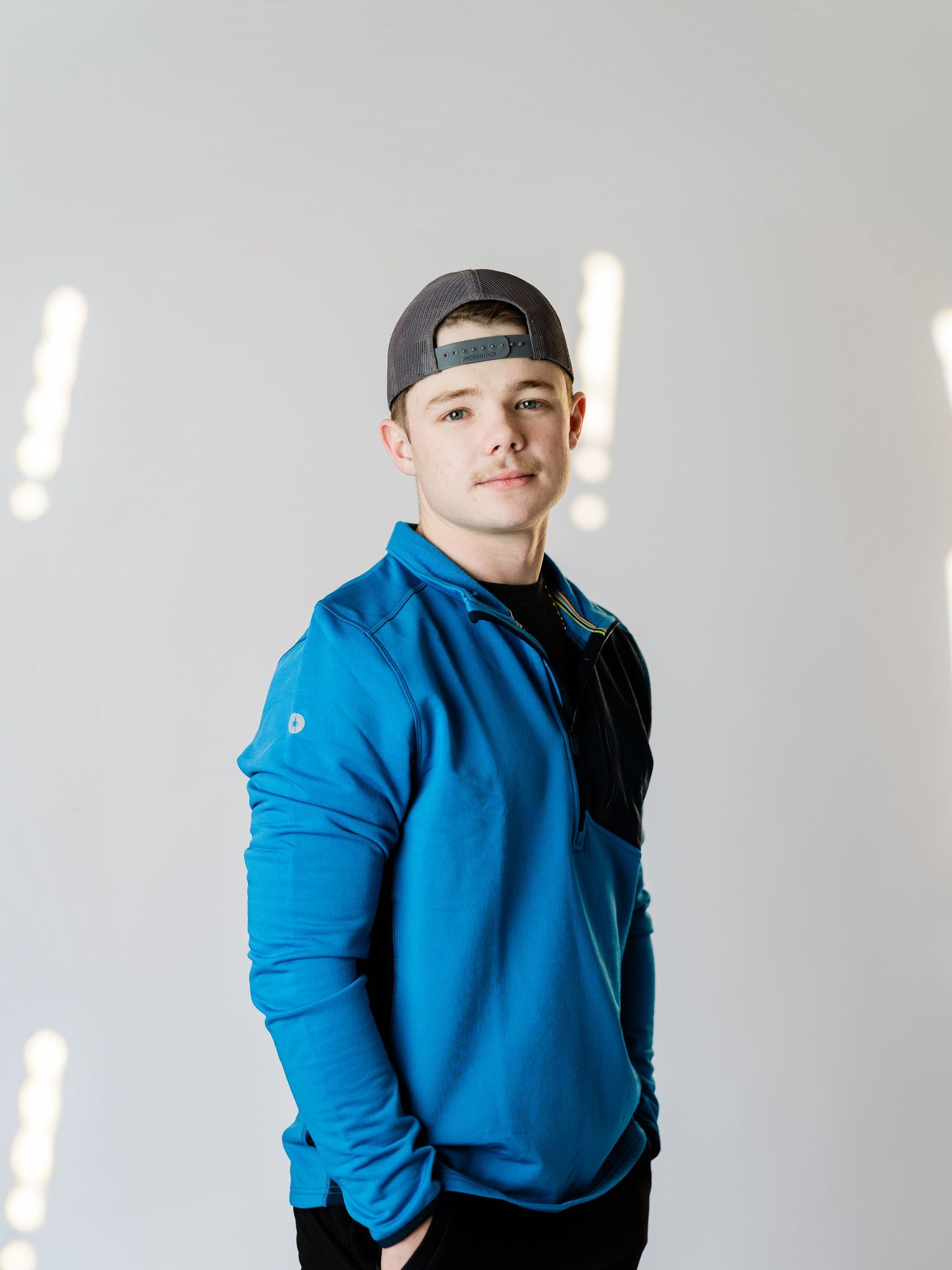 Person in bright blue hoodie strikes playful poses against white background.