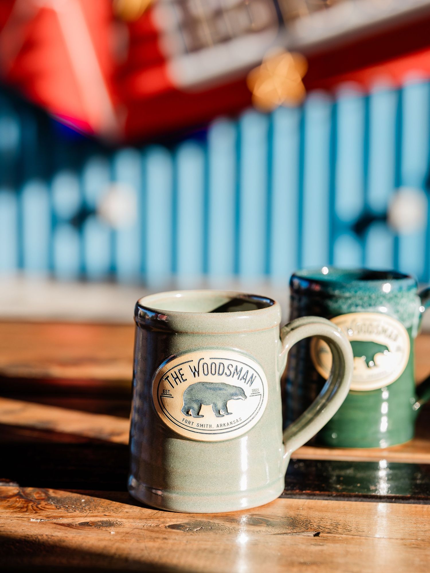 A series of handcrafted ceramic mugs with woodland animal designs displayed on a rustic wooden surface in warm lighting.