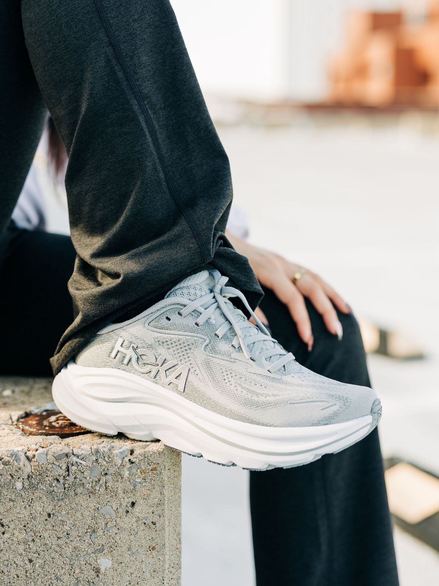 Gray athletic sneakers shown from multiple angles on concrete surface in lifestyle product photography.