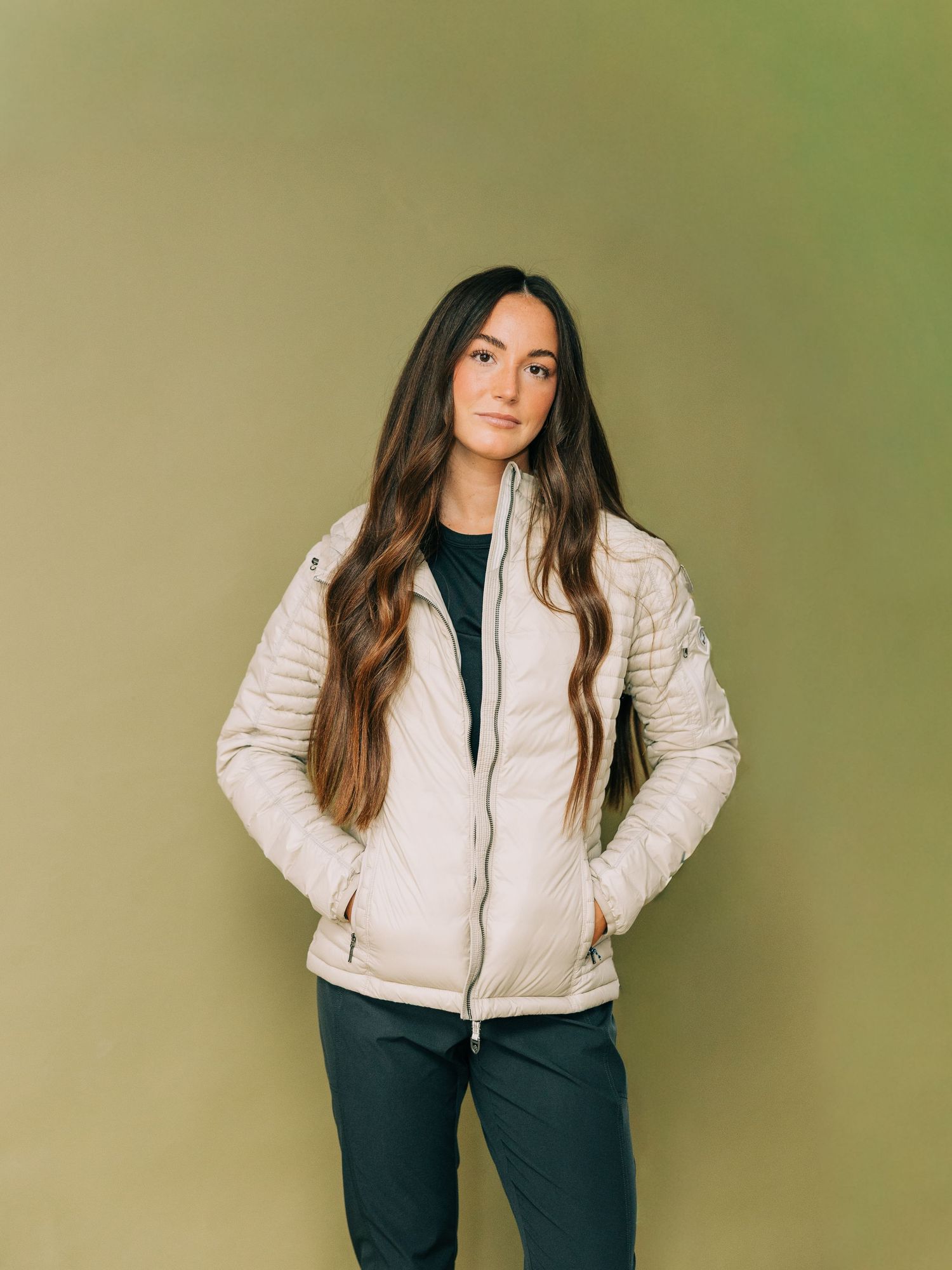 A figure in a cream puffer jacket and black pants poses in different positions against a green-tinted backdrop.