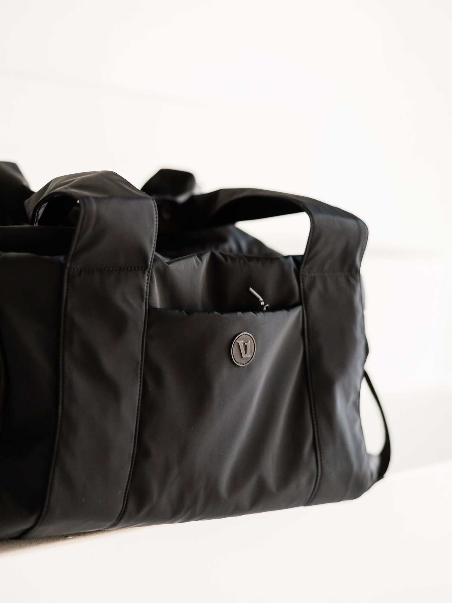 Black Lululemon duffle bag with side pocket and logo detail on white background.