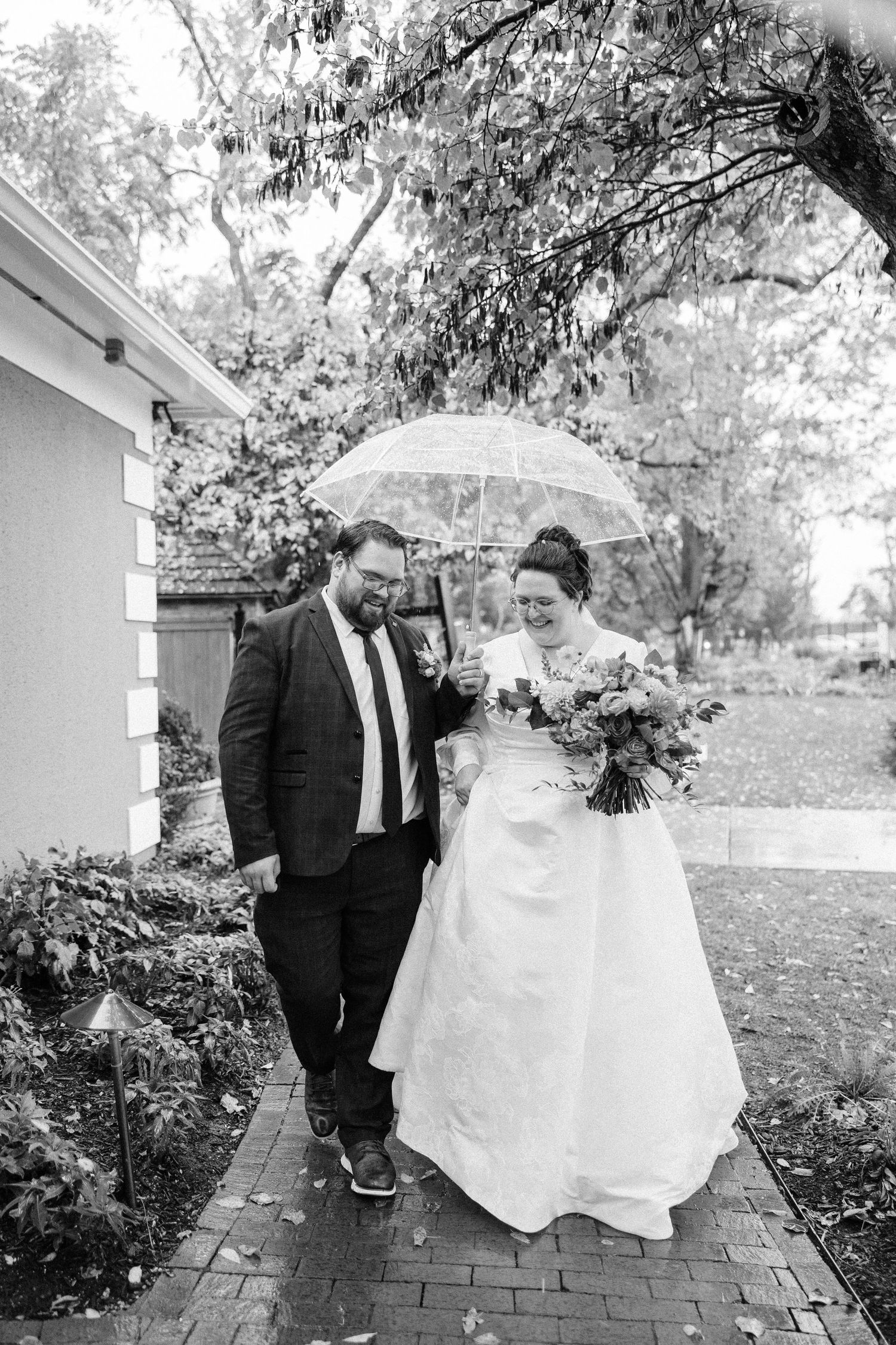 A series of black and white wedding photos showing a couple walking along a brick pathway in a garden setting.