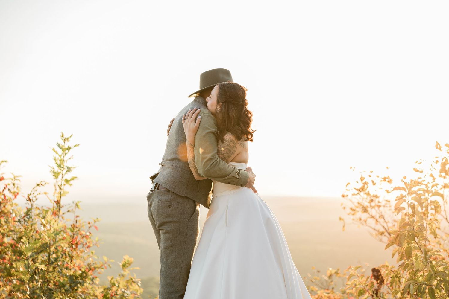 A romantic sunset wedding moment captured on a mountain overlook with golden light.