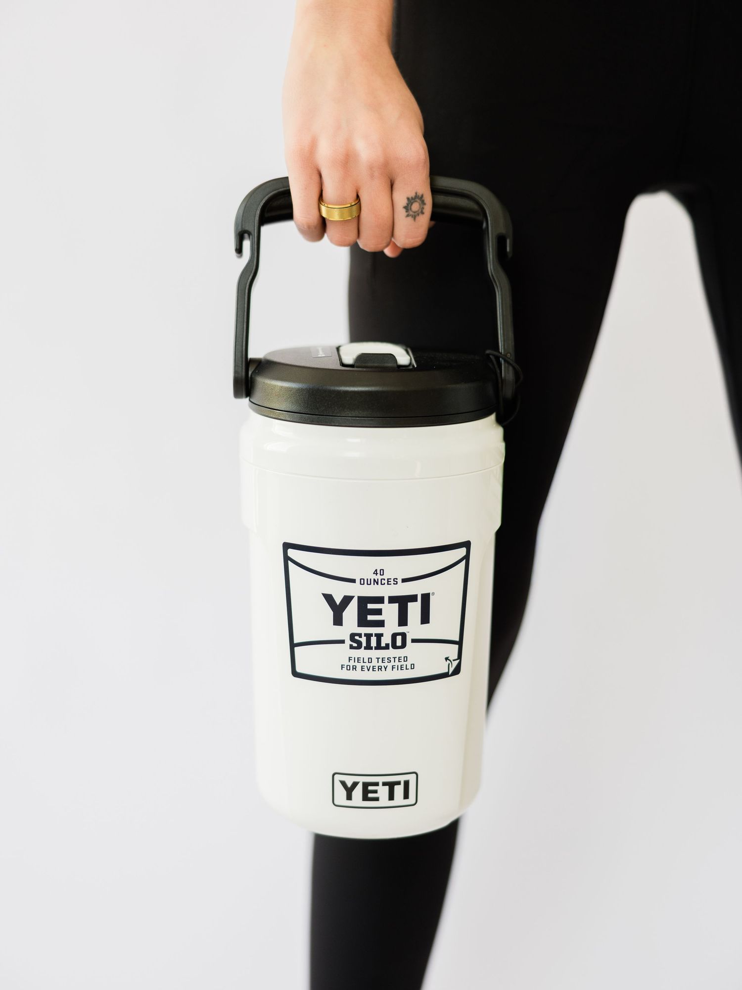 Person holding a white YETI Silo water jug with black handle and lid, featuring bold YETI branding on the front.