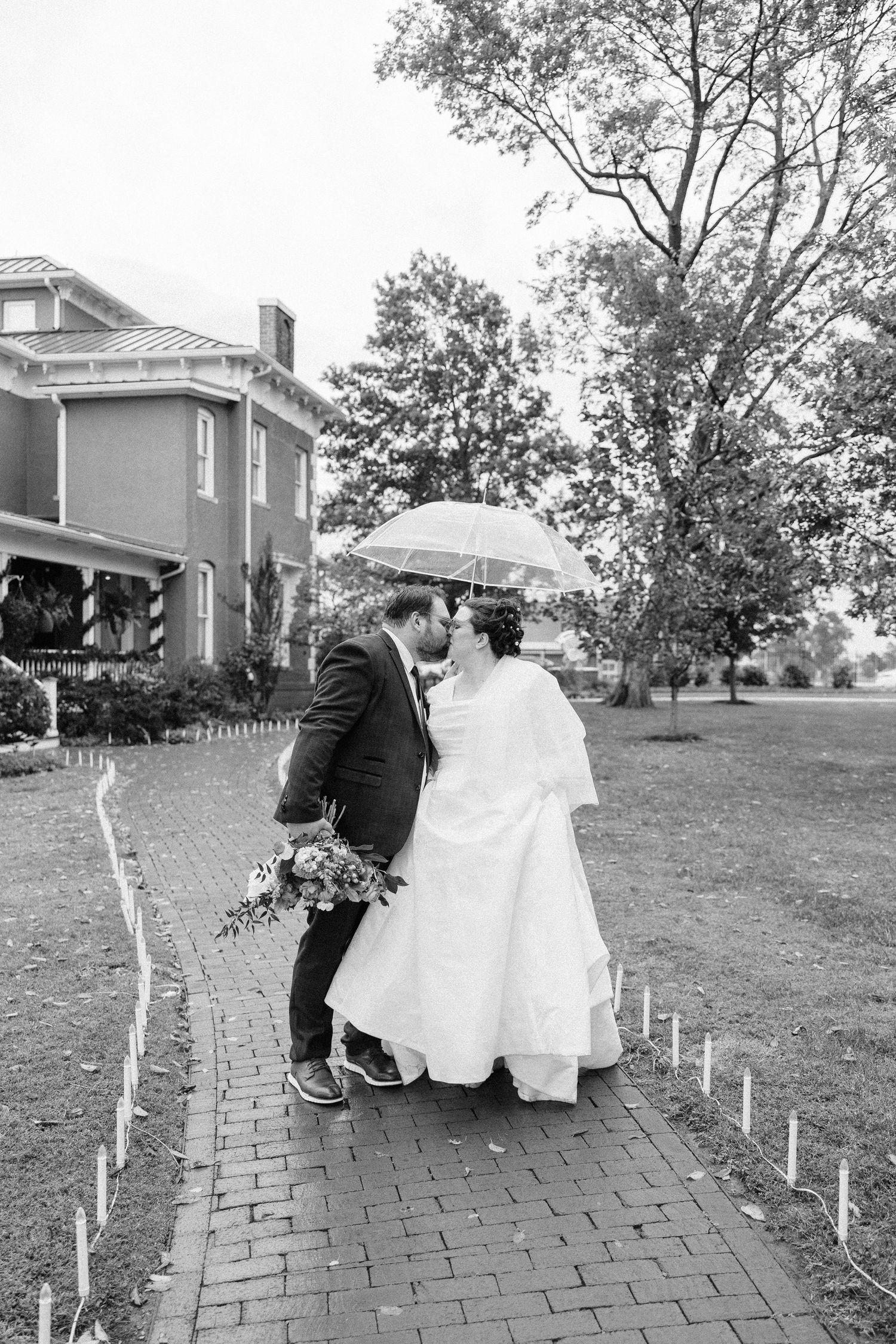 Black and white wedding sequence showing couple walking along a brick path with white stakes.