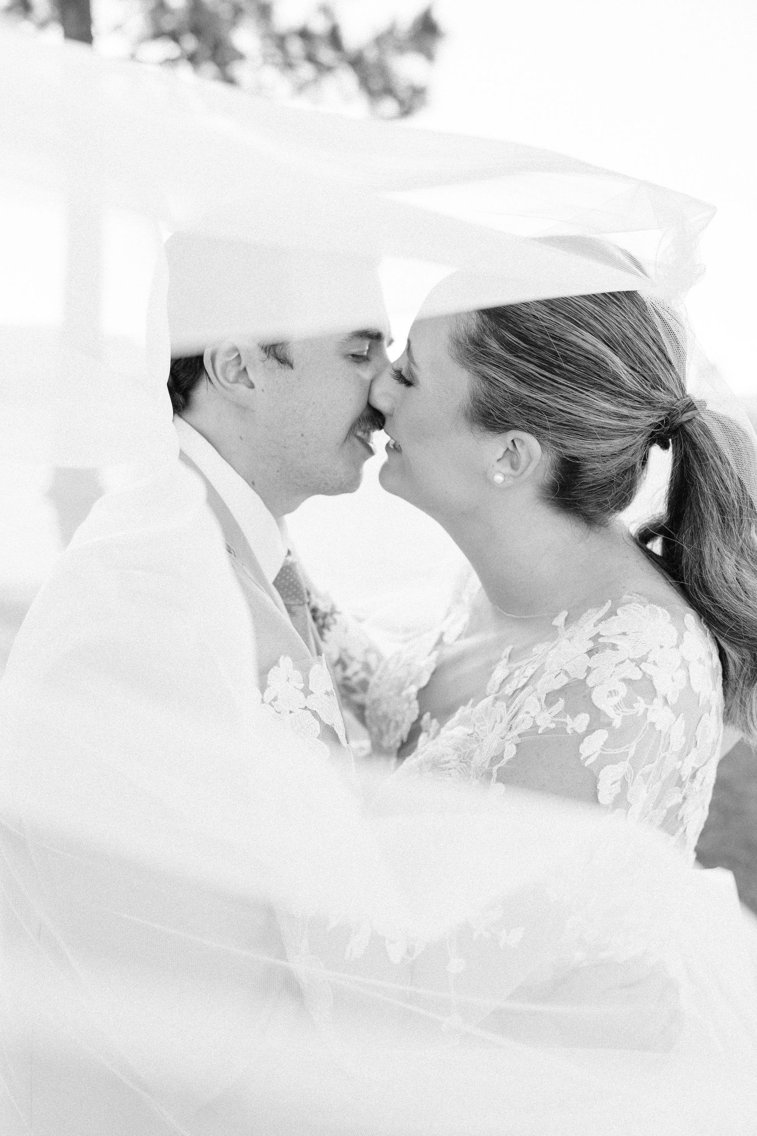 A series of intimate black and white wedding kiss photographs captured in soft lighting.