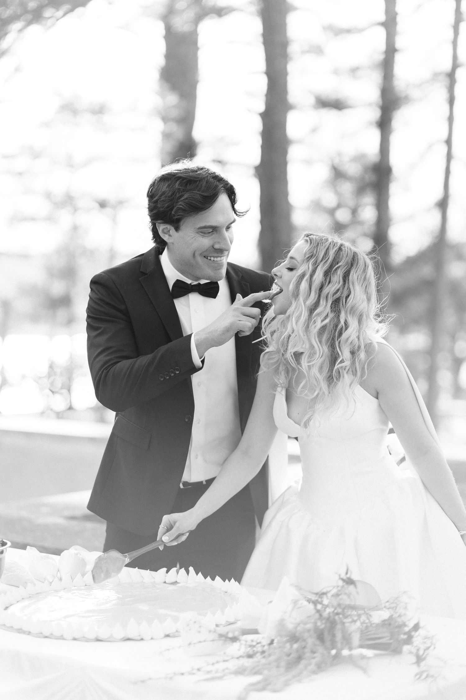 A romantic black and white wedding photo of a couple lying in the snow looking at each other lovingly.