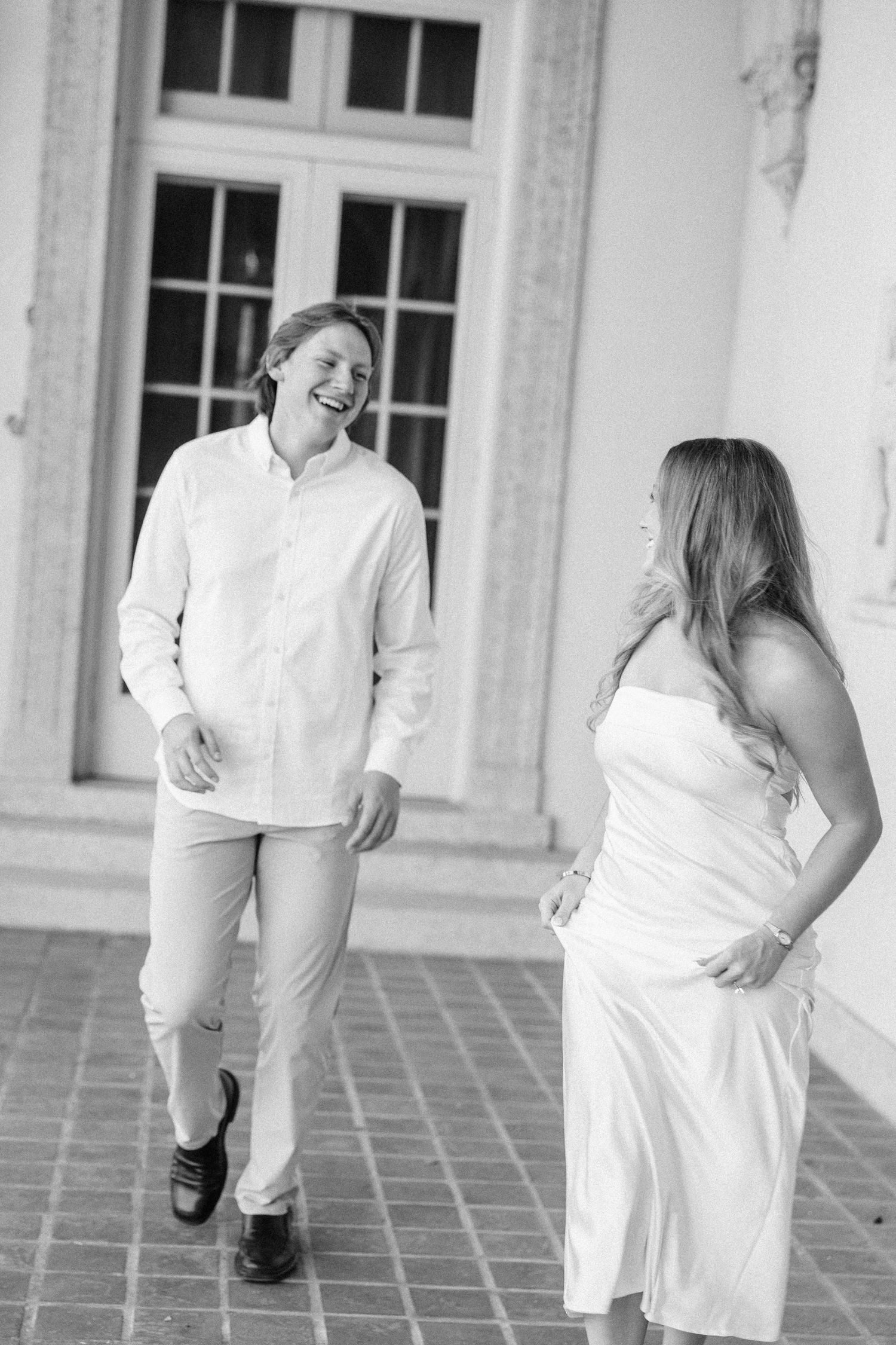 A series of black and white photos showing a couple in white clothing dancing and laughing together on a tiled patio.