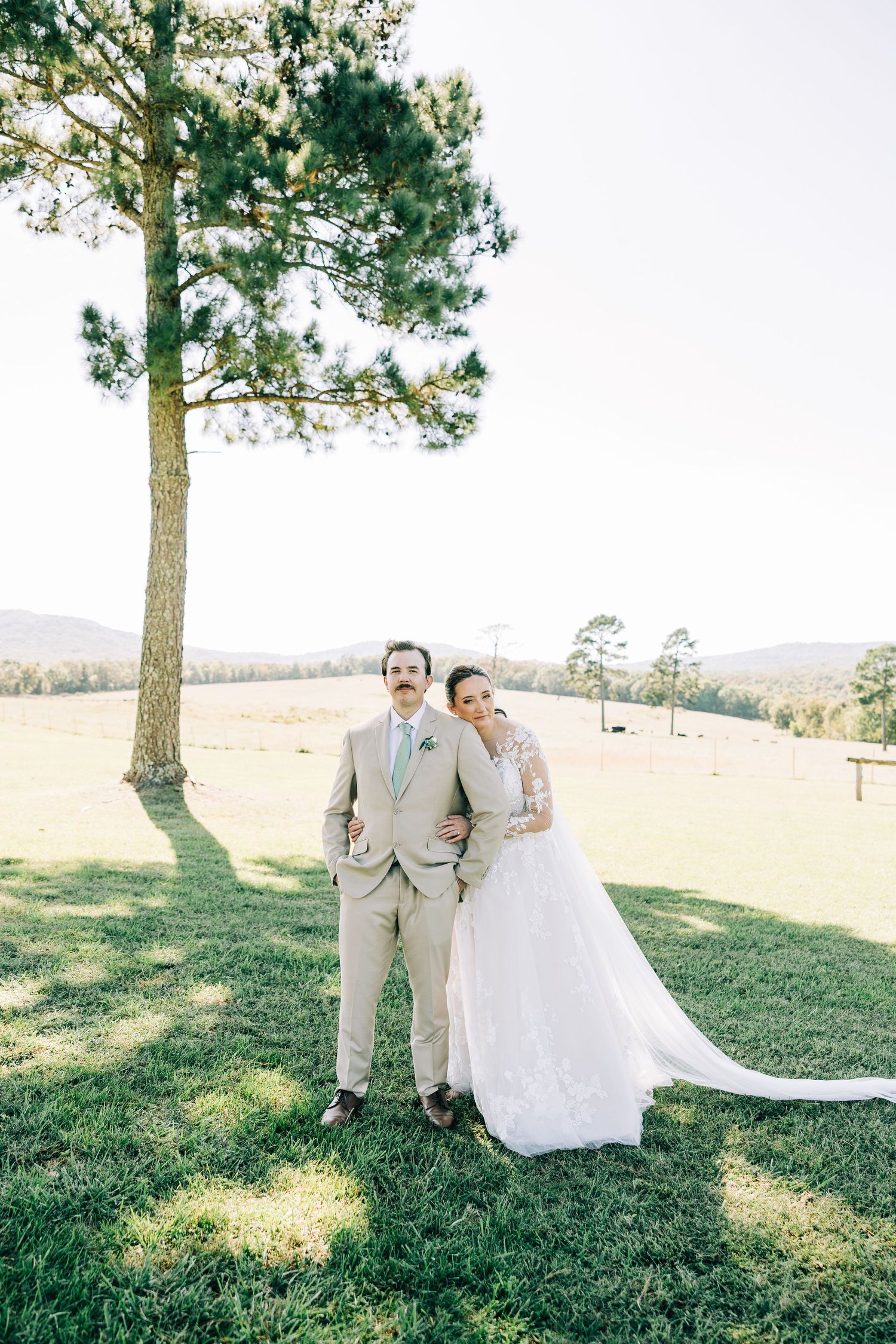 Newlyweds pose for romantic portraits under pine trees in an outdoor setting.