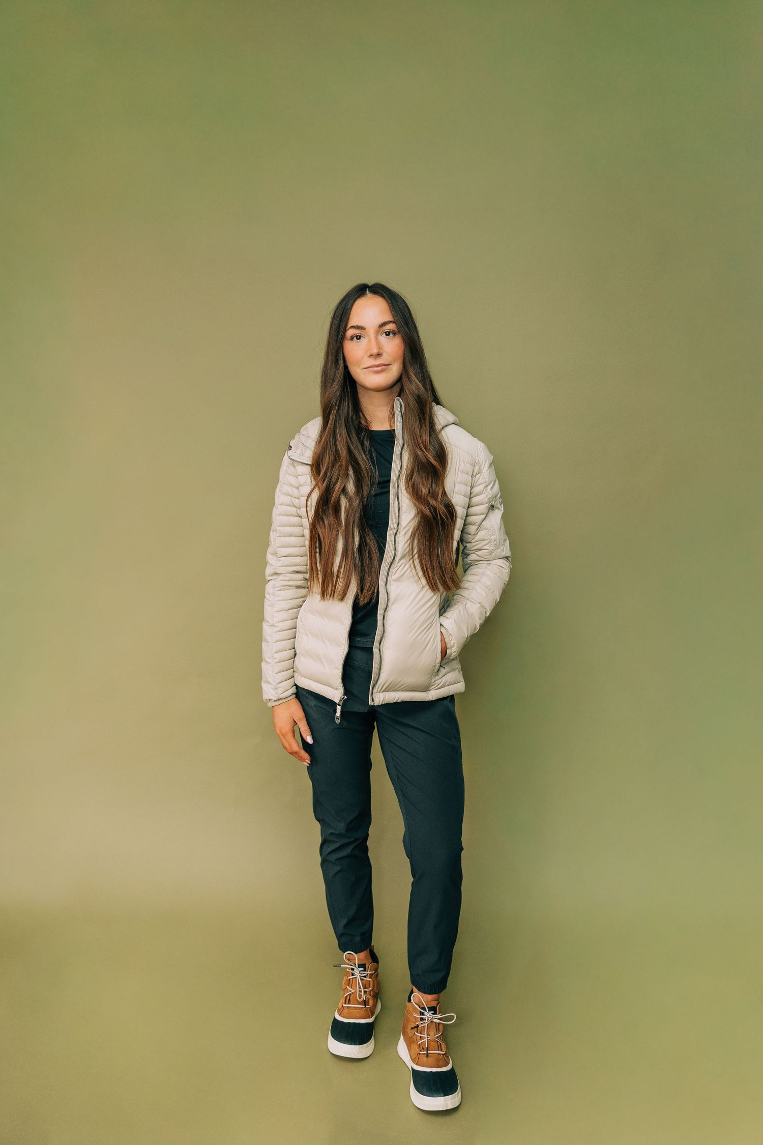 Fashion model poses in beige bomber jacket and dark pants against green background in progressive sequence of poses.