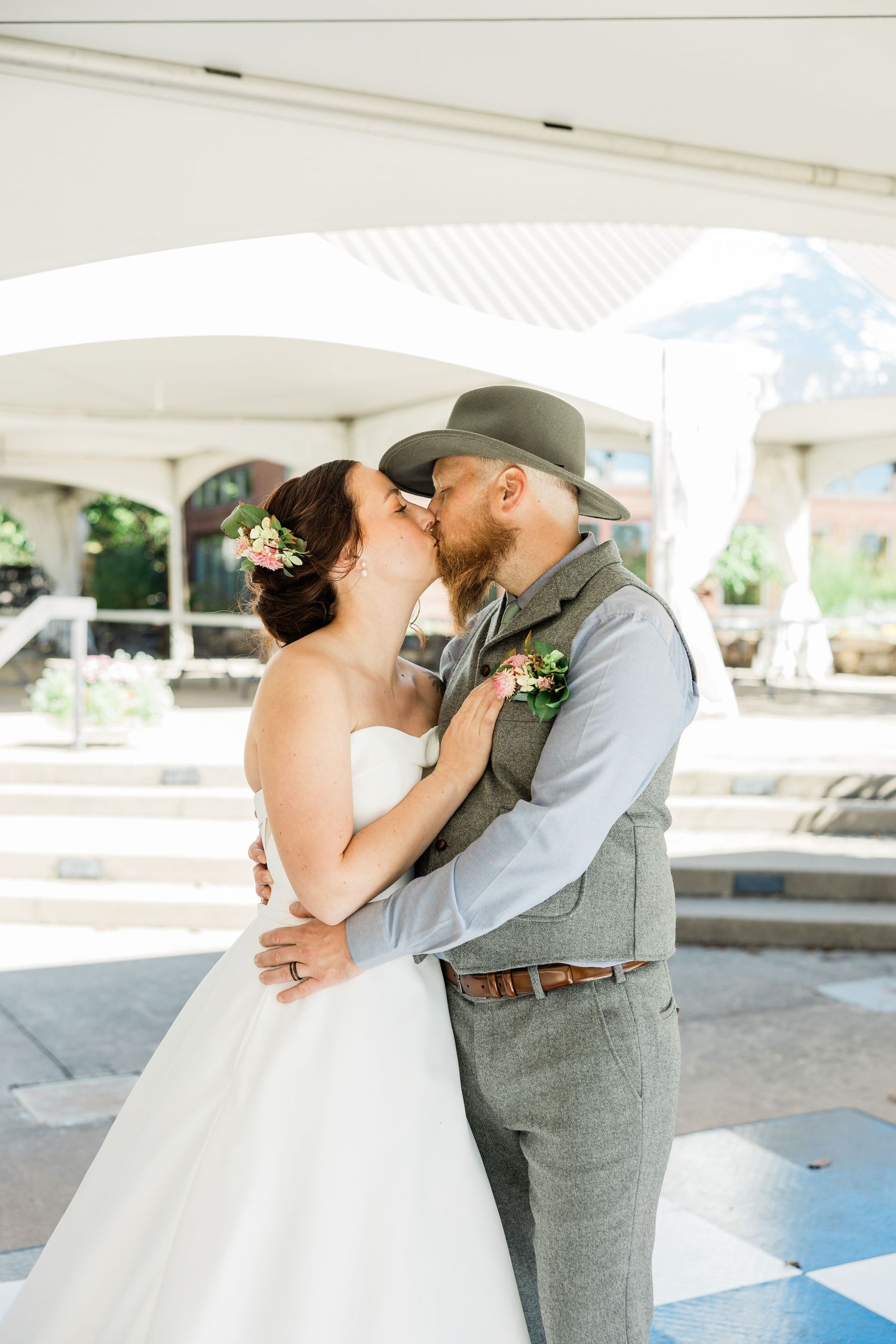 Romantic first dance moment captured under a white reception tent at an outdoor wedding venue.