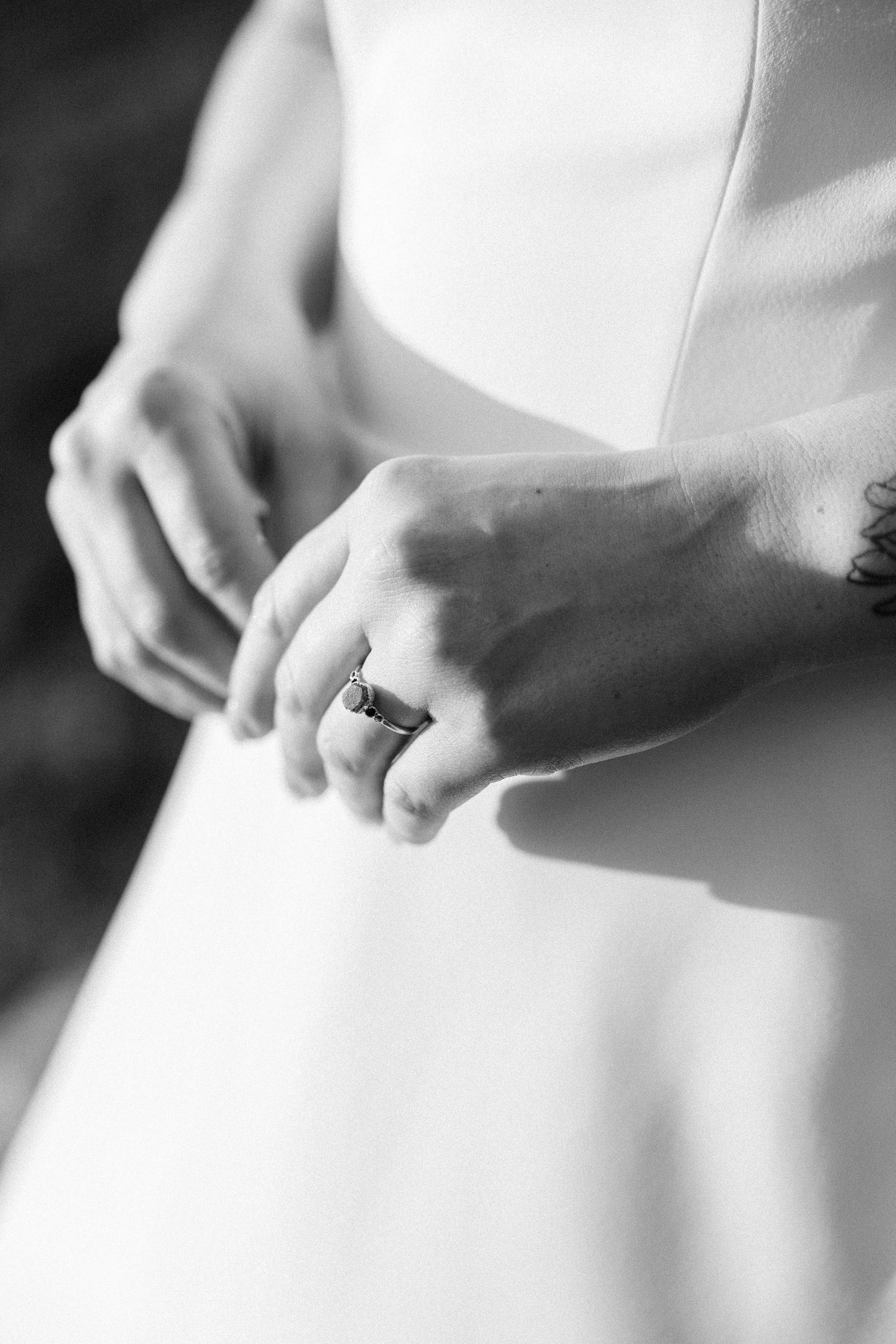 Close-up details of a white wedding dress fabric showing delicate texture and pleating in black and white.