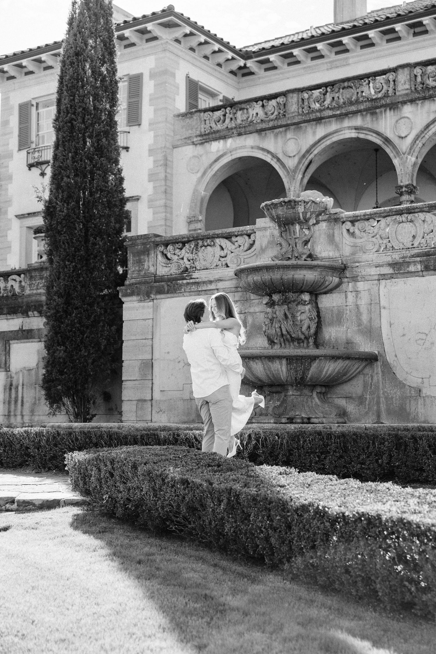 A series of black and white architectural photos showing ornate stone buildings with cypress trees and manicured hedges.