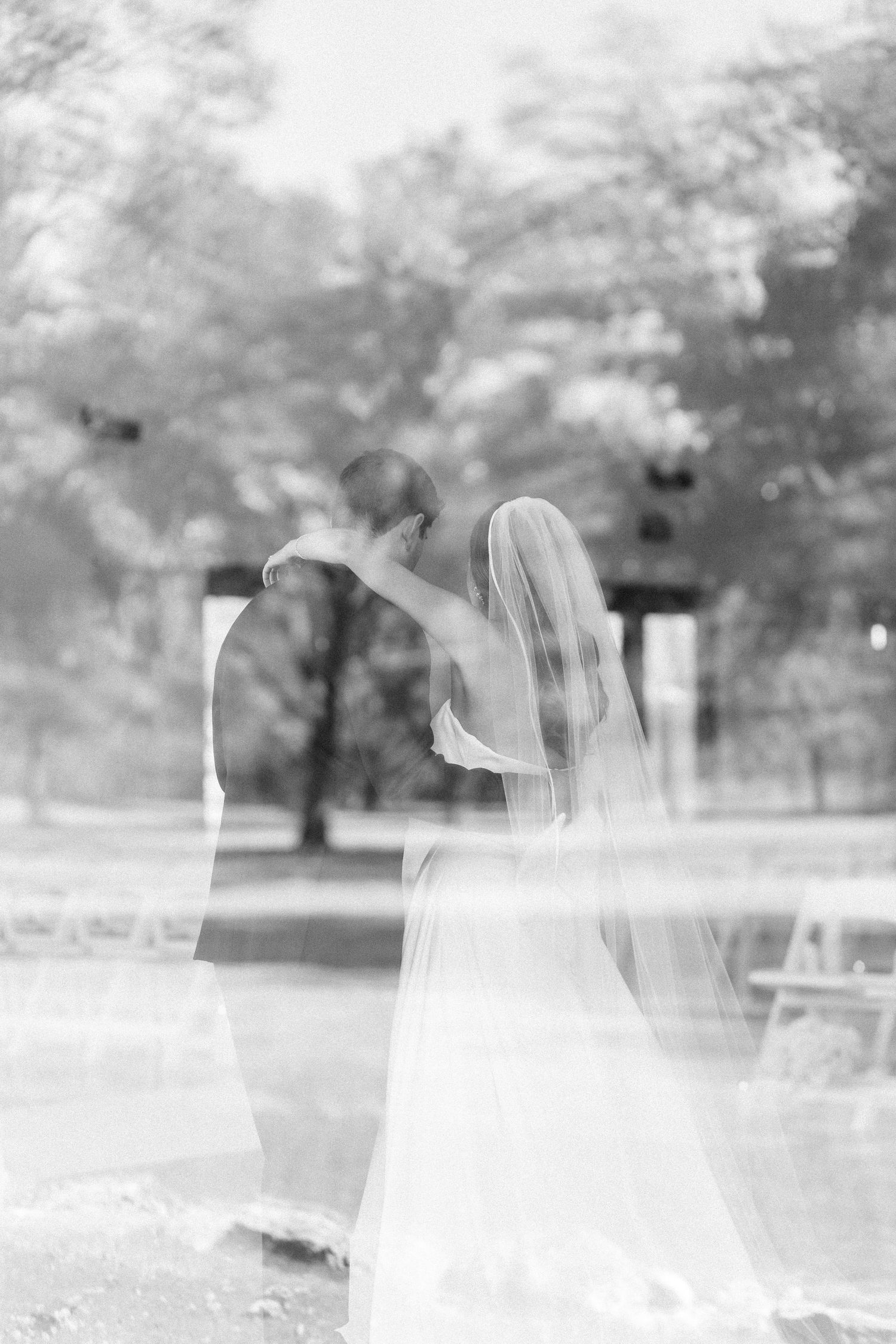 Multiple exposure shot creates dreamy effect of flowing white wedding dress in outdoor setting.