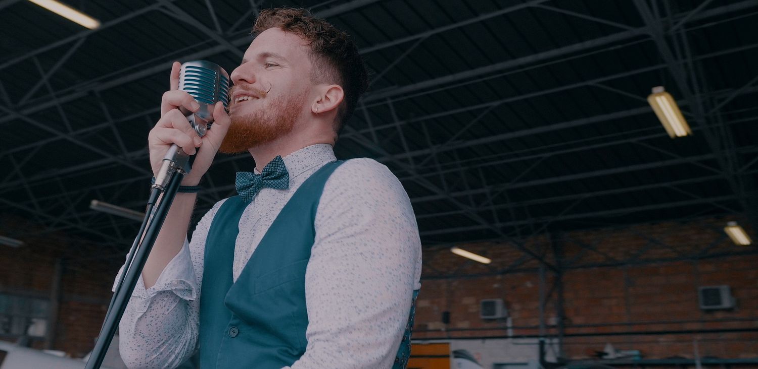 Homme chantant dans un microphone vintage lors d'une performance dans un aérodrome - Jacket - Pop