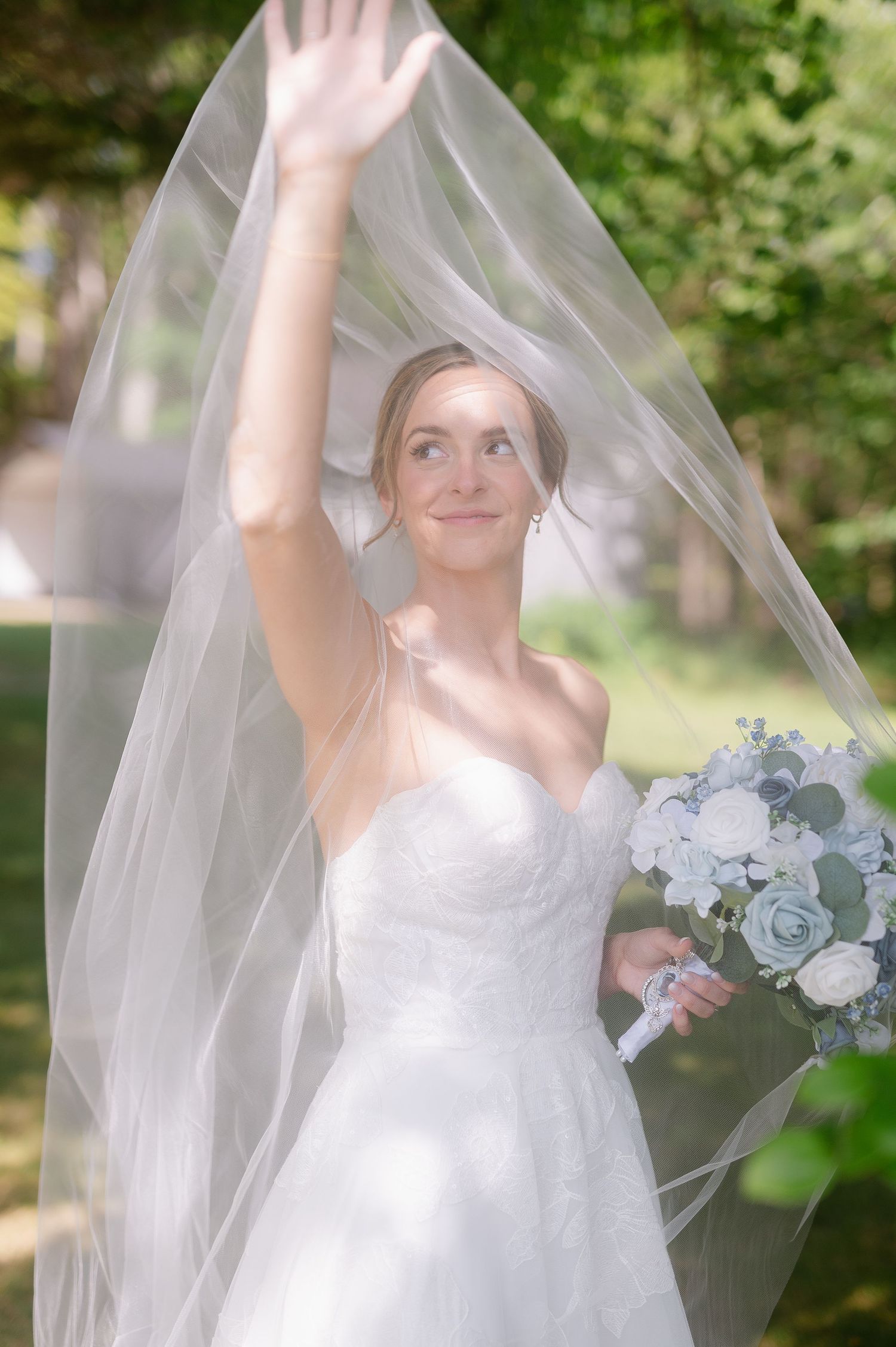 Ethereal bridal portrait with flowing veil and delicate white and blue bouquet.