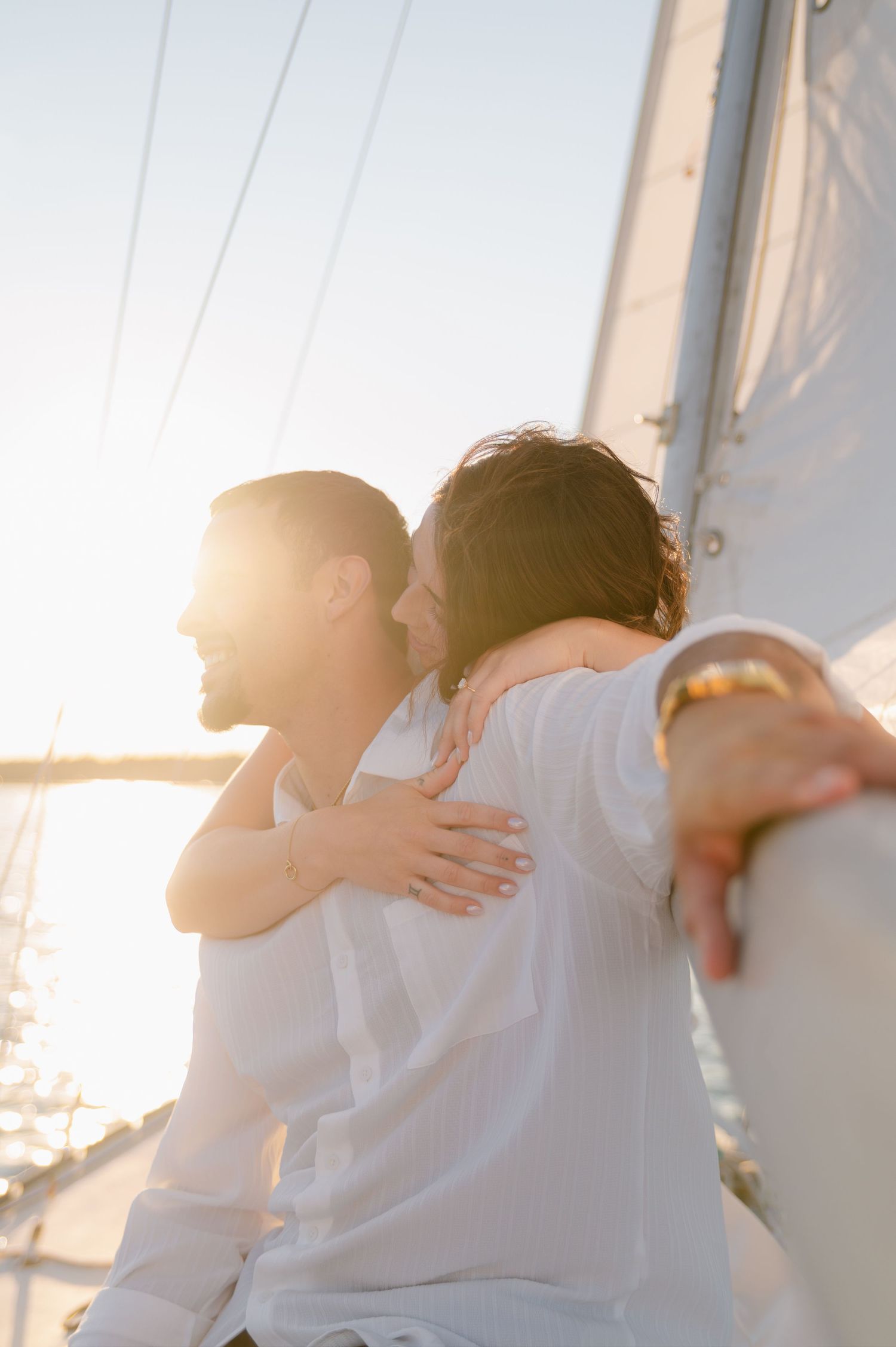 Sun-drenched photos of a couple embracing on a sailboat during golden hour.