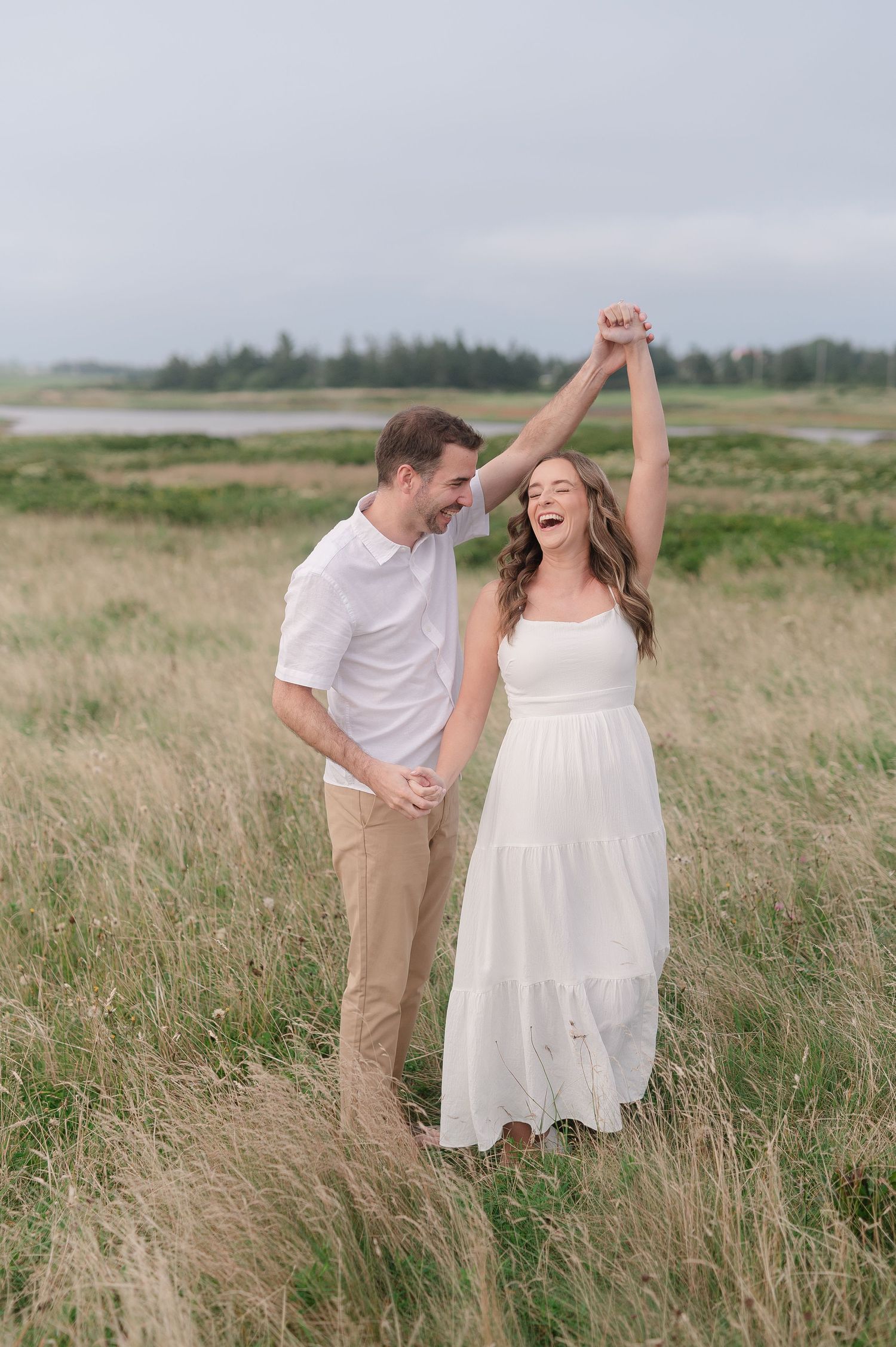 Couple laughing and dancing together in a rustic field setting.