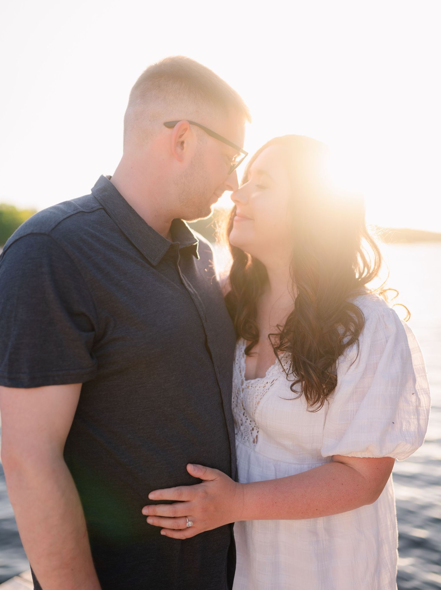 Intimate sunset photoshoot with couple in casual attire against bright backlighting.