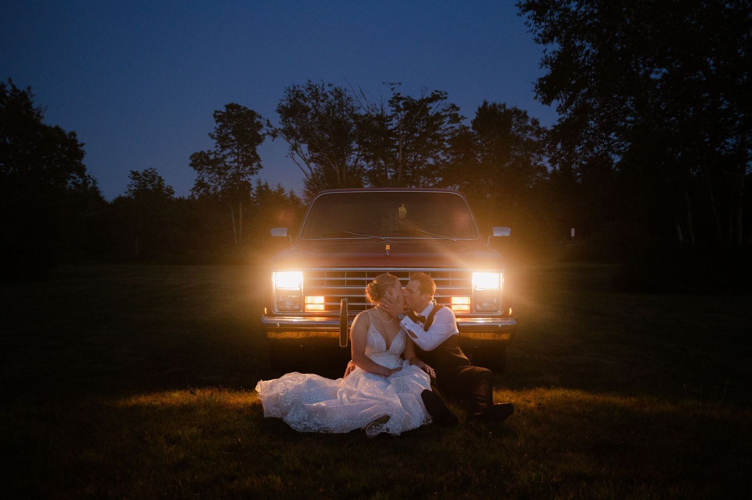 Dramatic nighttime wedding portraits with car headlights creating silhouettes.