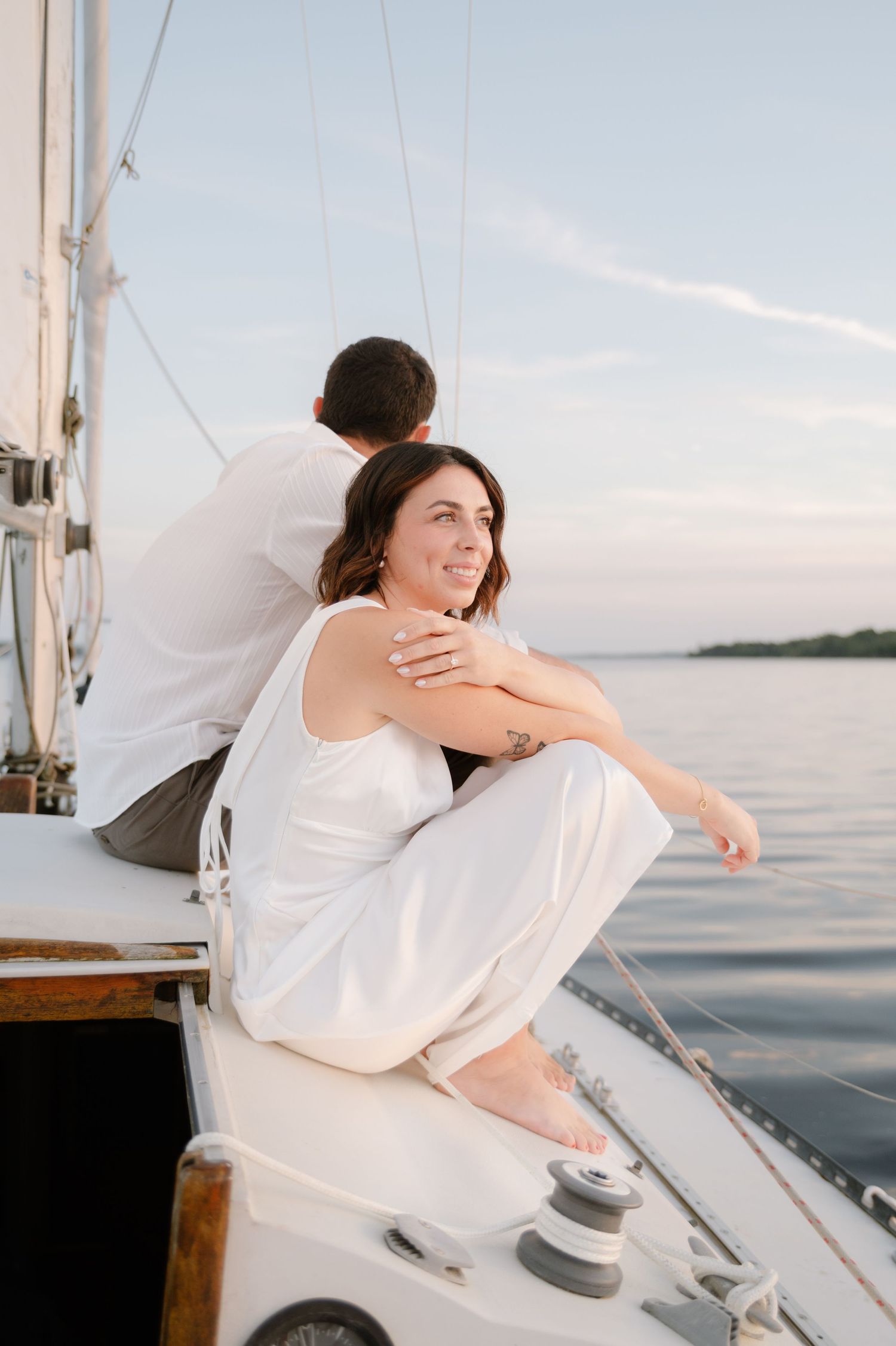 Playful moments shared between a couple on a sailboat deck with water views.