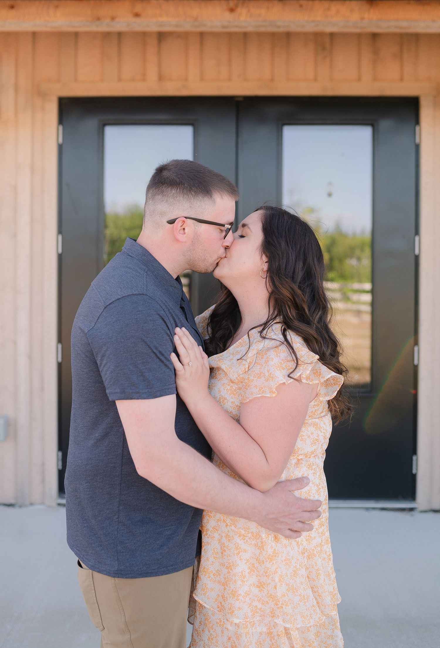 A couple shares a romantic moment in front of a rustic wooden building.