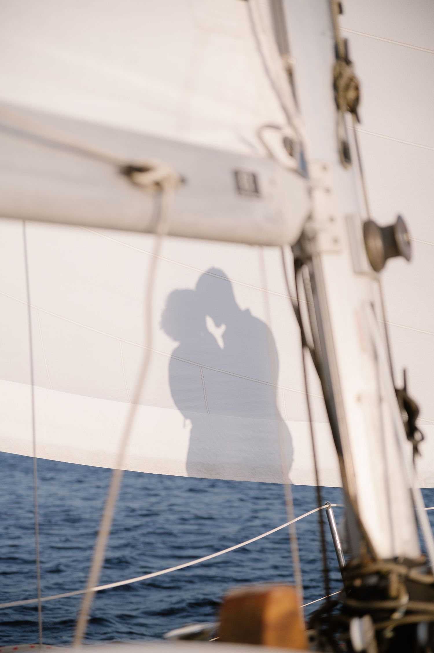 Silhouettes of a couple against the ocean backdrop on a sailboat deck.