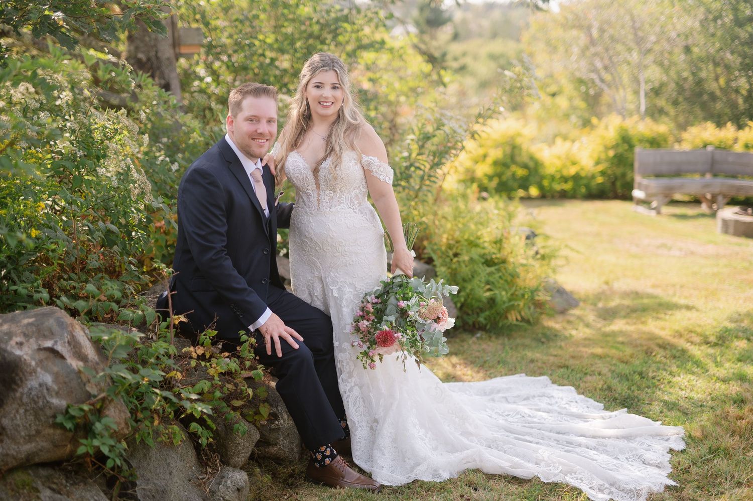 A couple shares a romantic moment in a garden setting during their wedding day, surrounded by lush greenery.