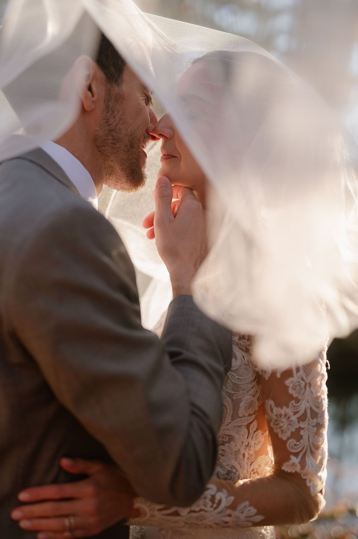 An intimate wedding moment captured through delicate white veil fabric.