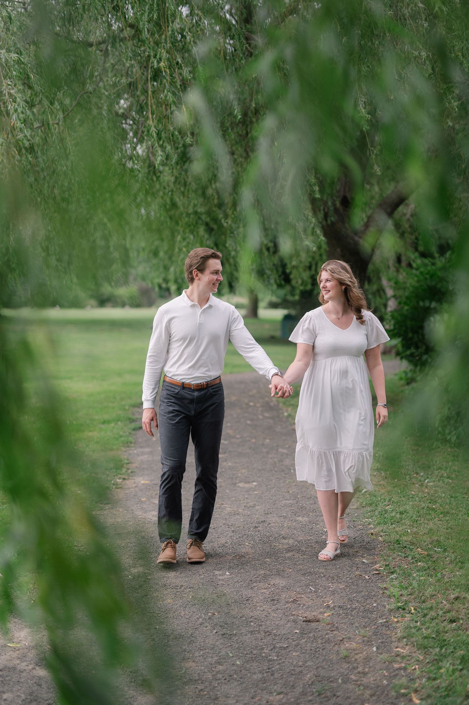Couple walking playfully along a tree-lined path.