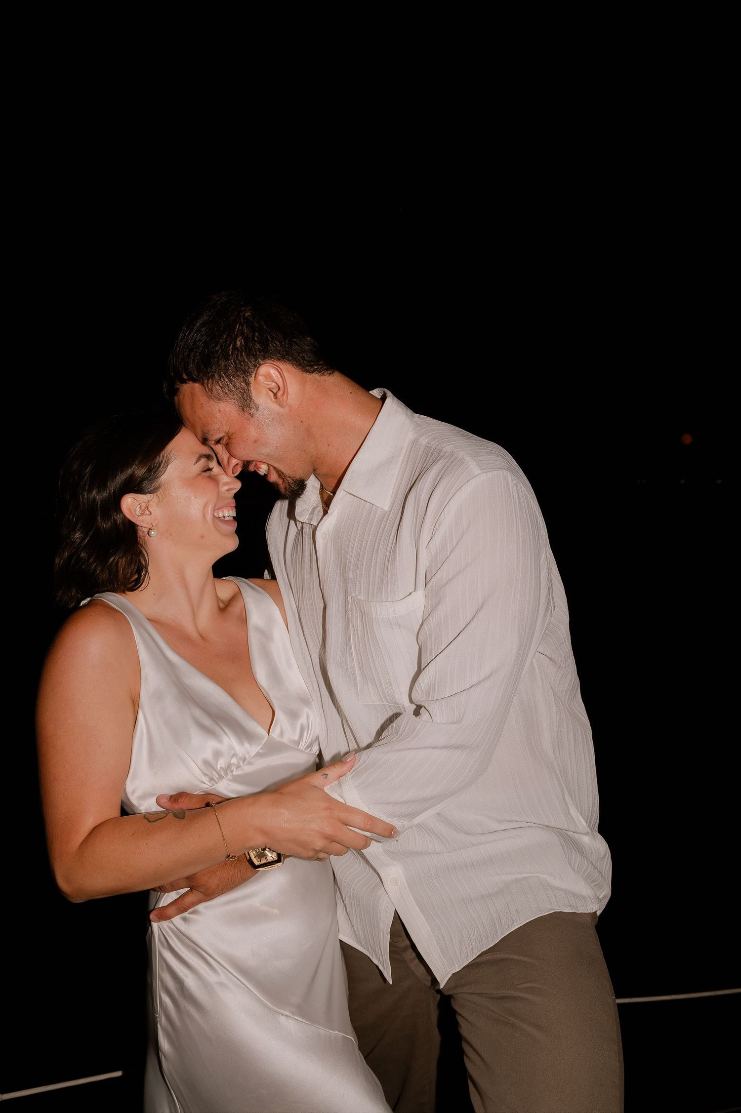 Intimate nighttime photos of a couple in white clothing sharing romantic moments.