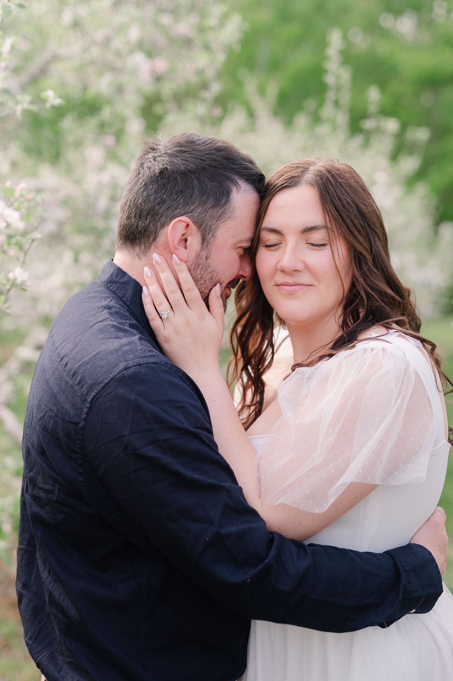 Intimate spring engagement photos captured among blooming trees.