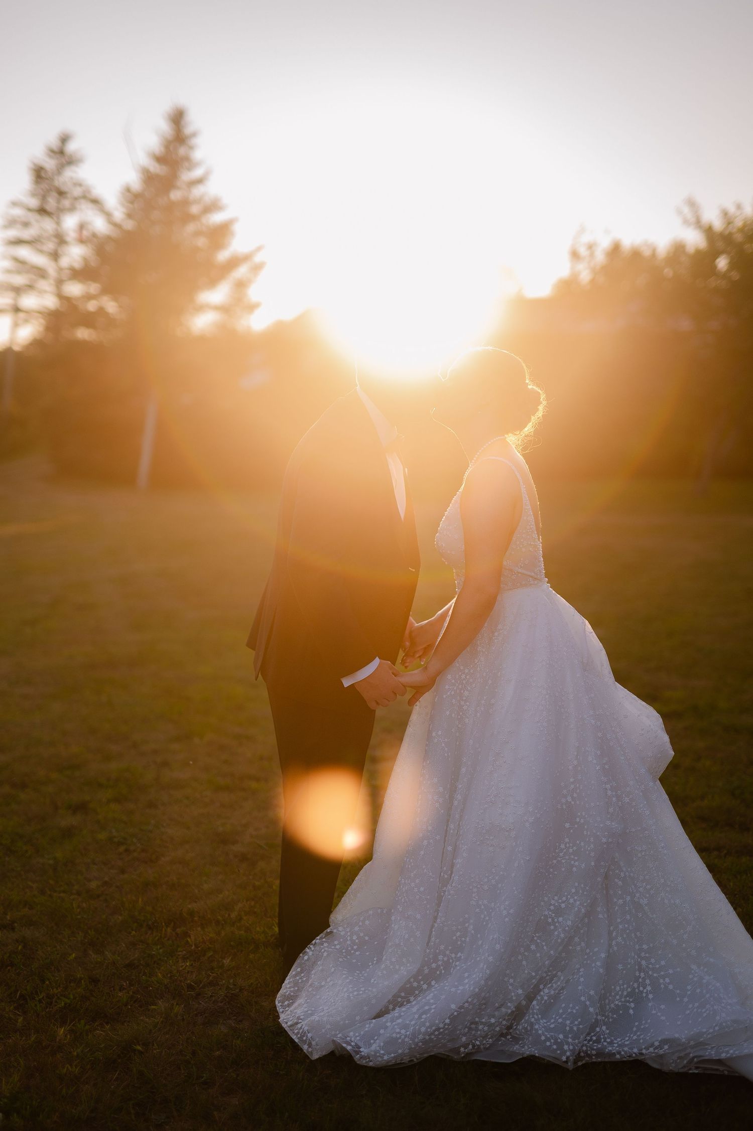 Silhouetted wedding couple embraces in dramatic golden sunset lighting.