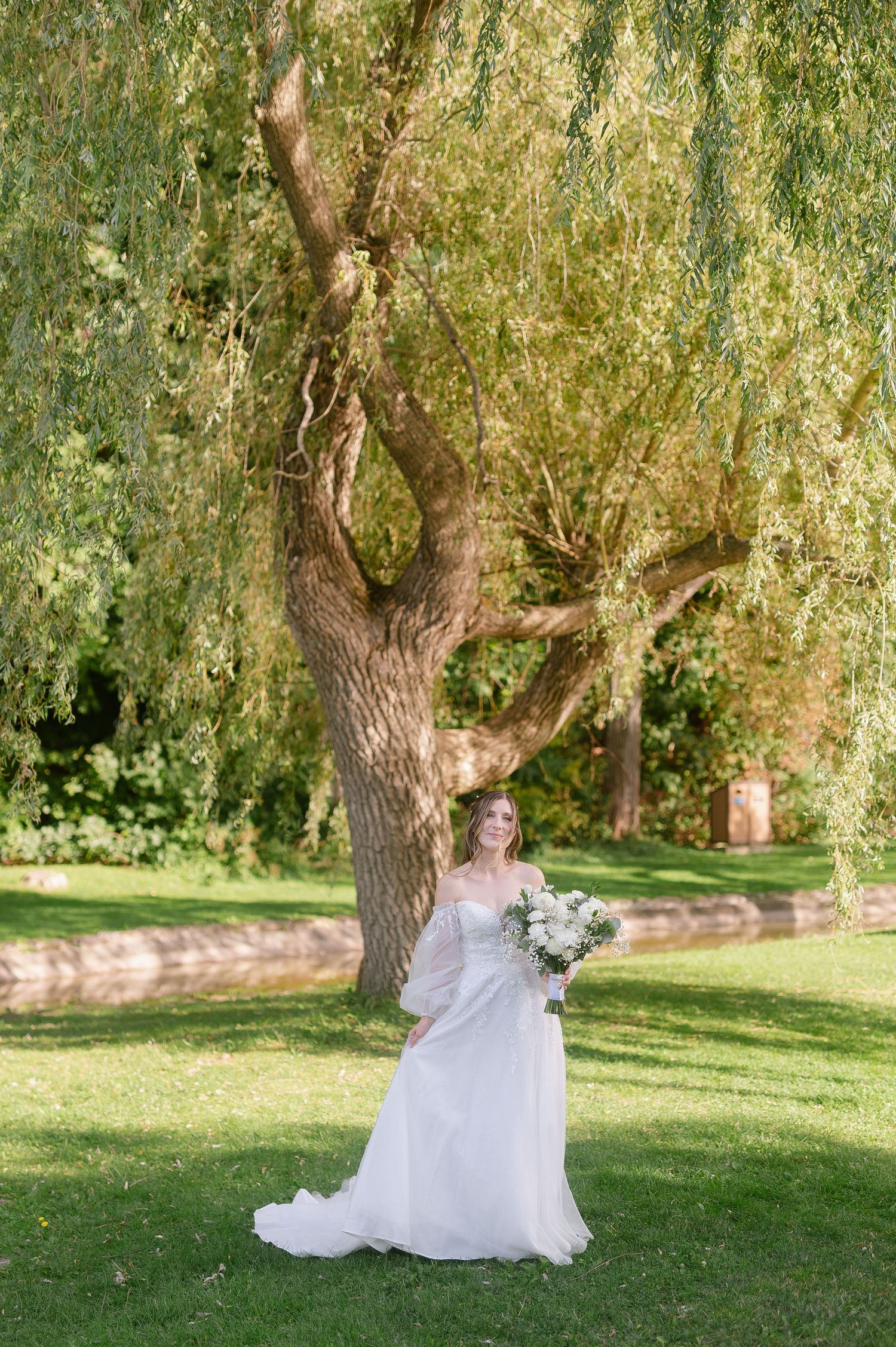 Elegant bridal portraits under a weeping willow tree in a garden setting.