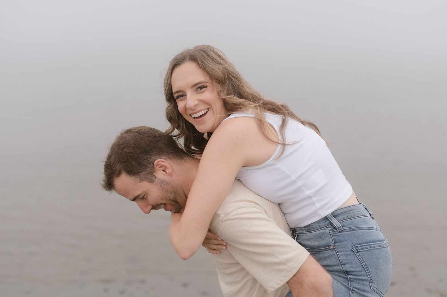 A couple dances and twirls playfully in a field on a cloudy day.
