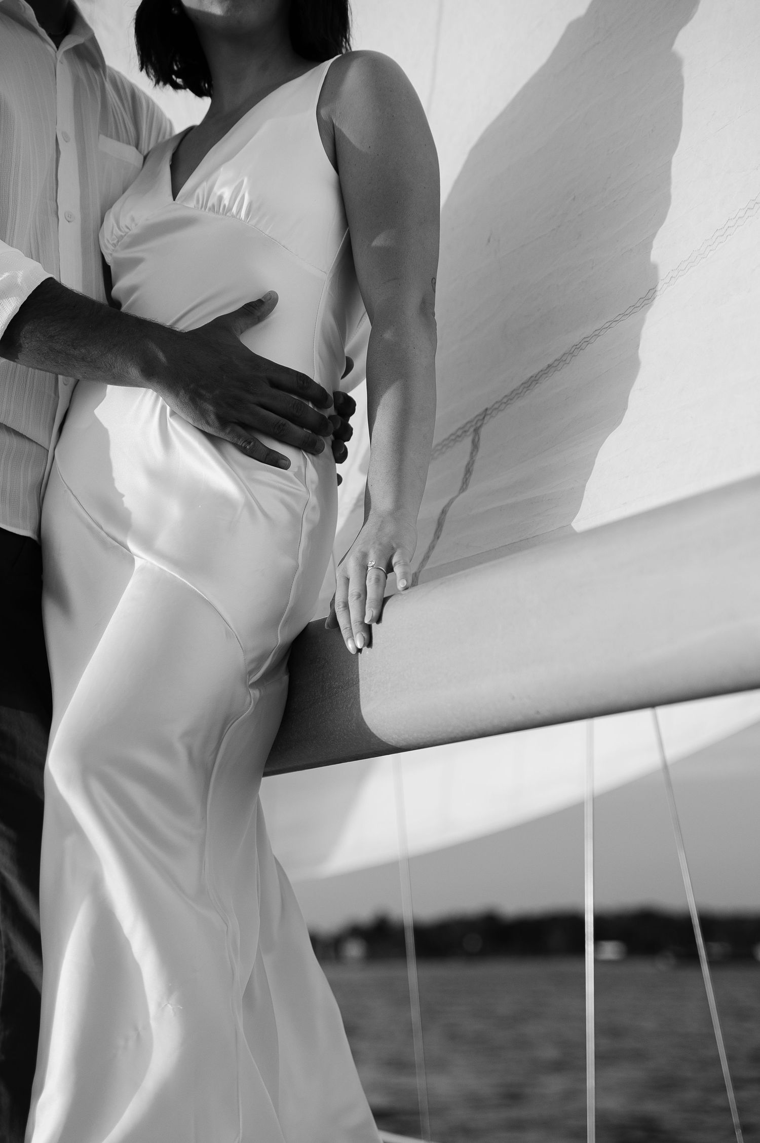 A romantic black and white photo series of a couple in white attire against a bright wall.