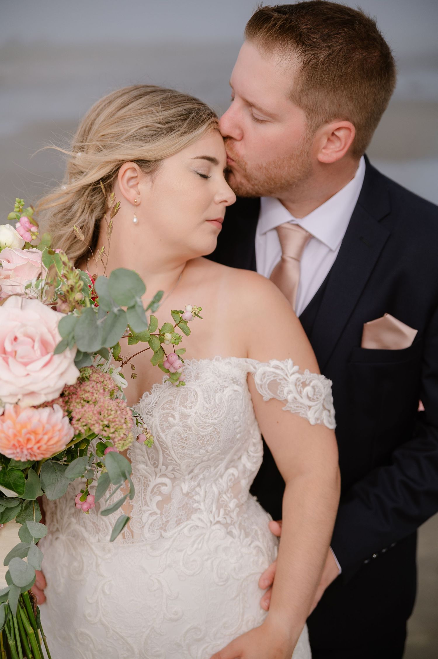 Intimate wedding portrait with delicate lace dress details and pink floral bouquet.