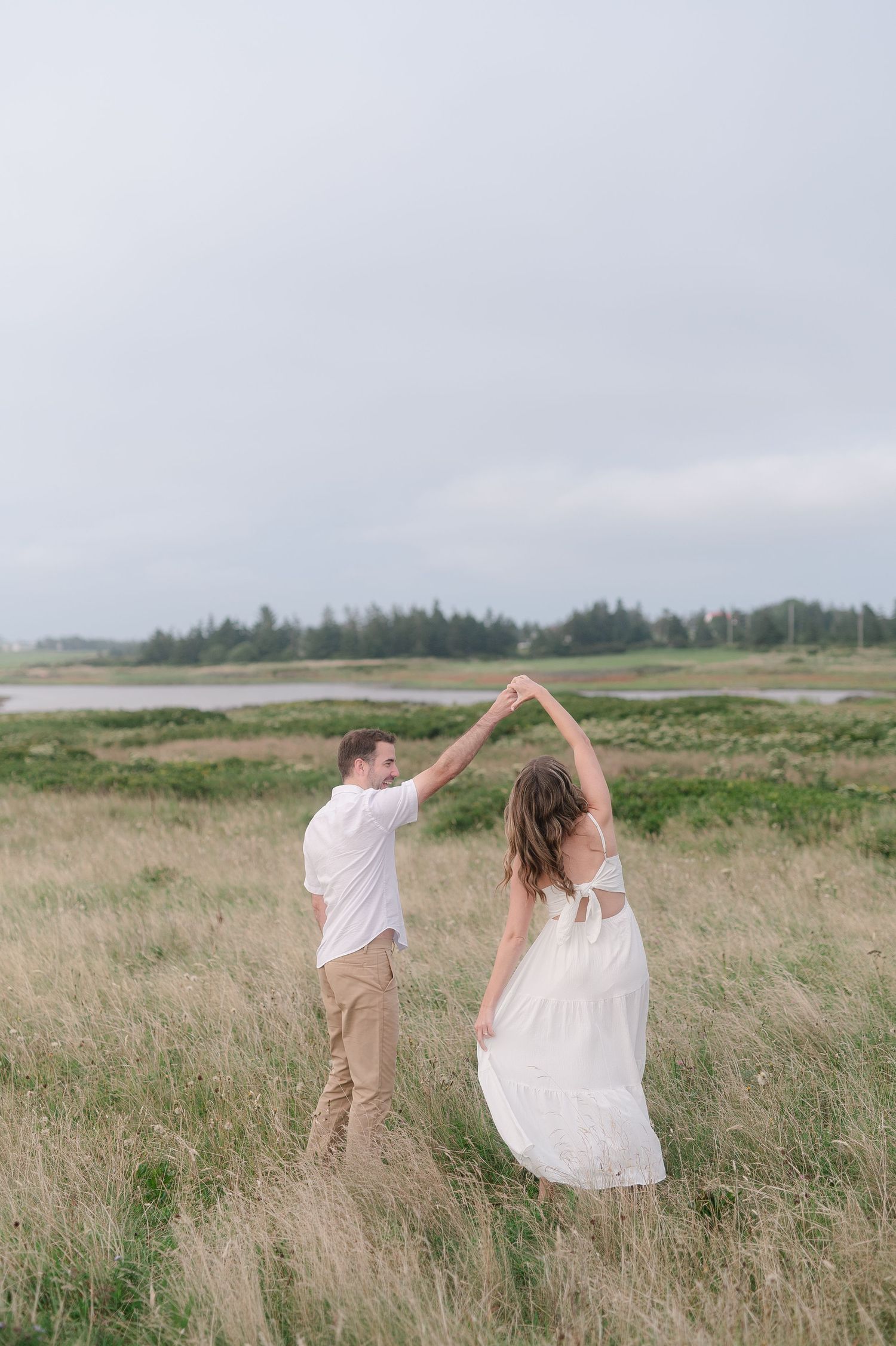 Dancing couple spins joyfully through a windswept coastal field.