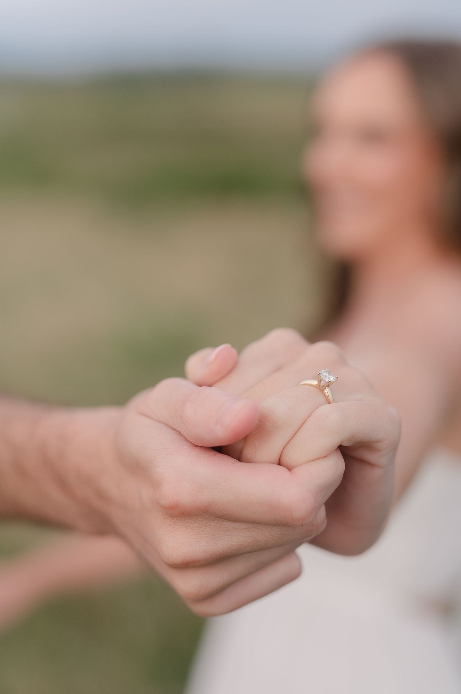 Close-up of hands holding and dancing together in an outdoor setting.