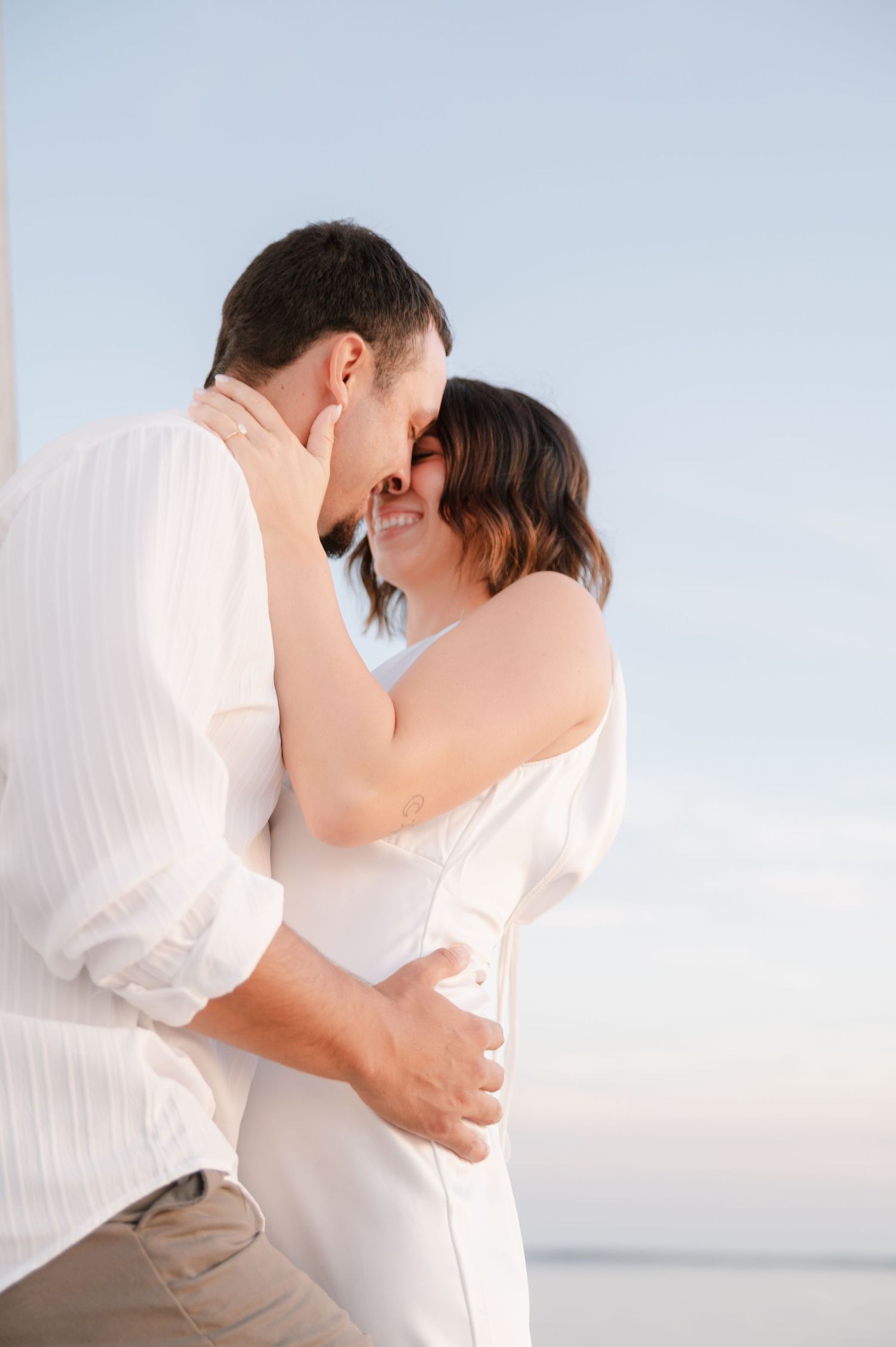 A tender embrace captured against the soft light and ocean backdrop on a sailing vessel.