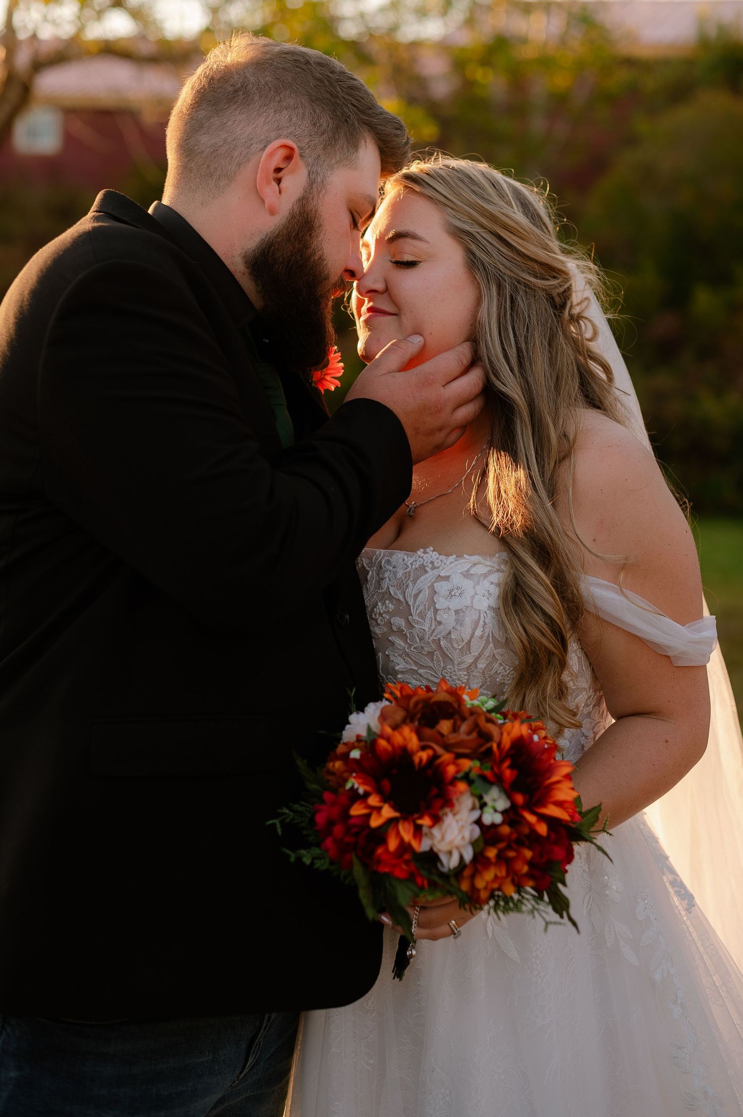 Intimate wedding moment at sunset with vibrant orange and white bouquet.