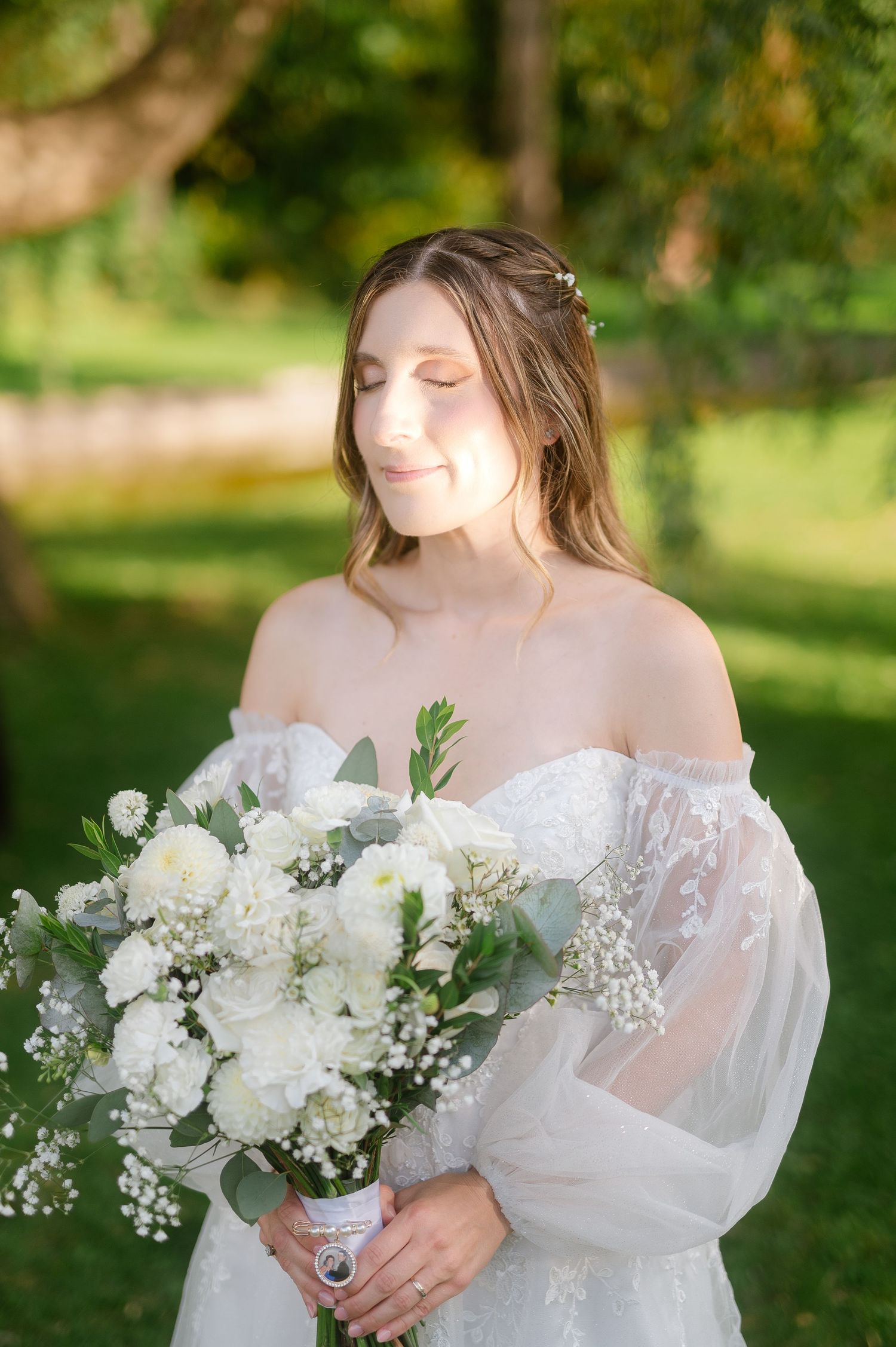 Bride holds a delicate white and green bouquet in an outdoor garden setting.