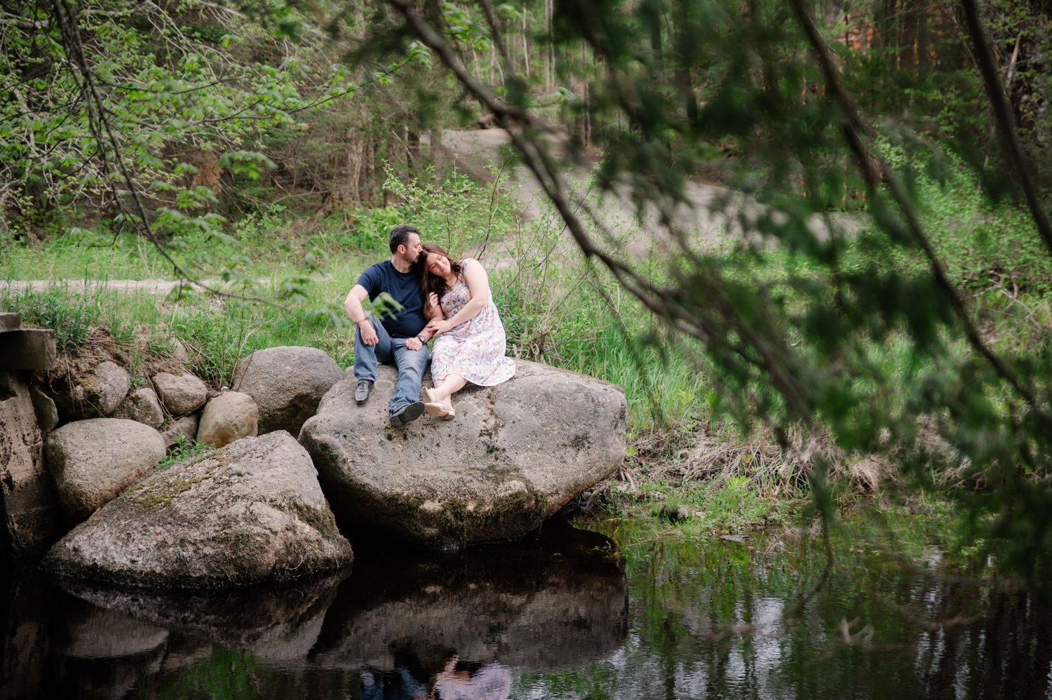 Romantic photo session by a pond with rocks and natural scenery.