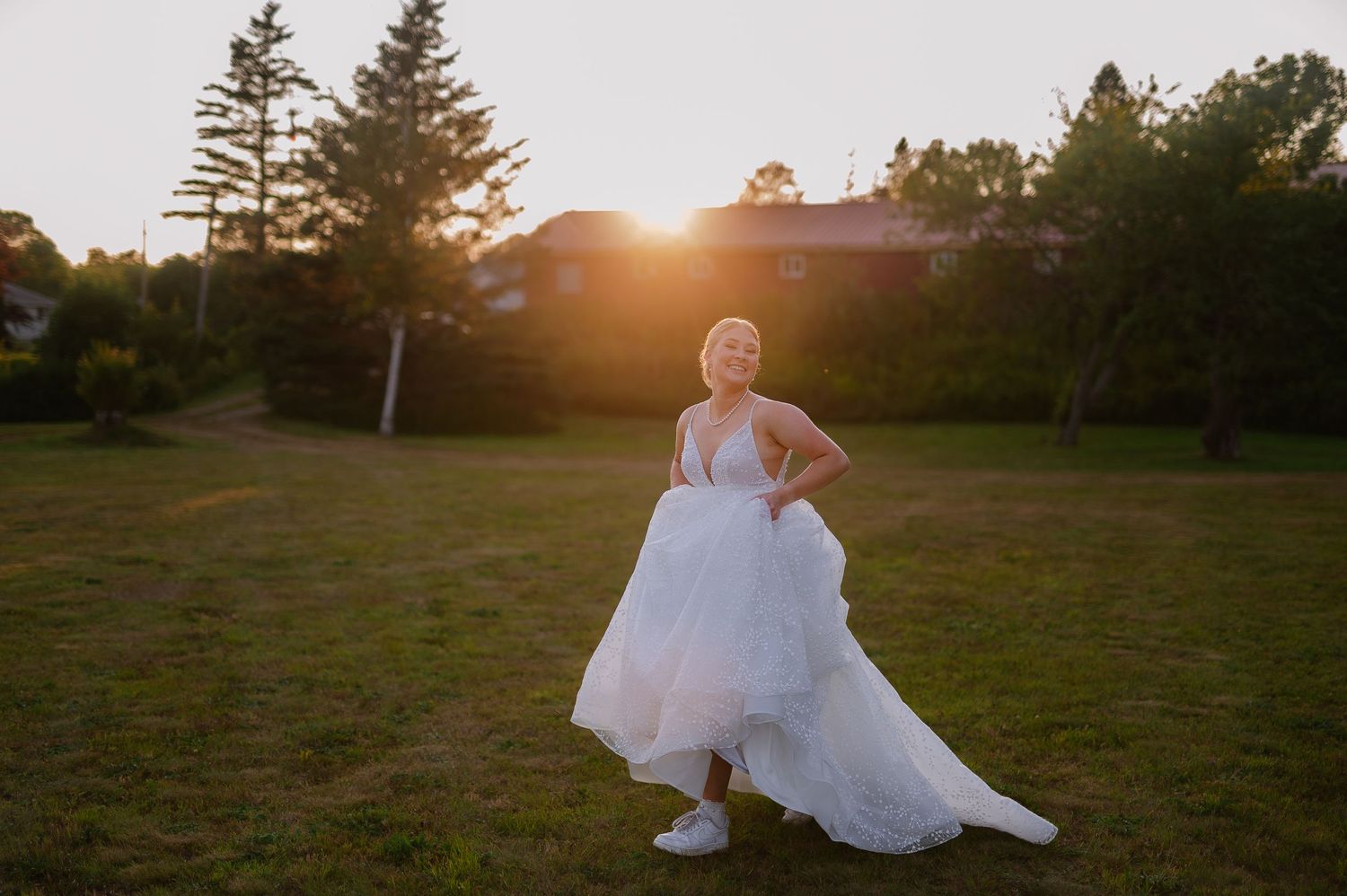 Romantic sunset wedding photos in a grassy field with evergreen trees in the background.