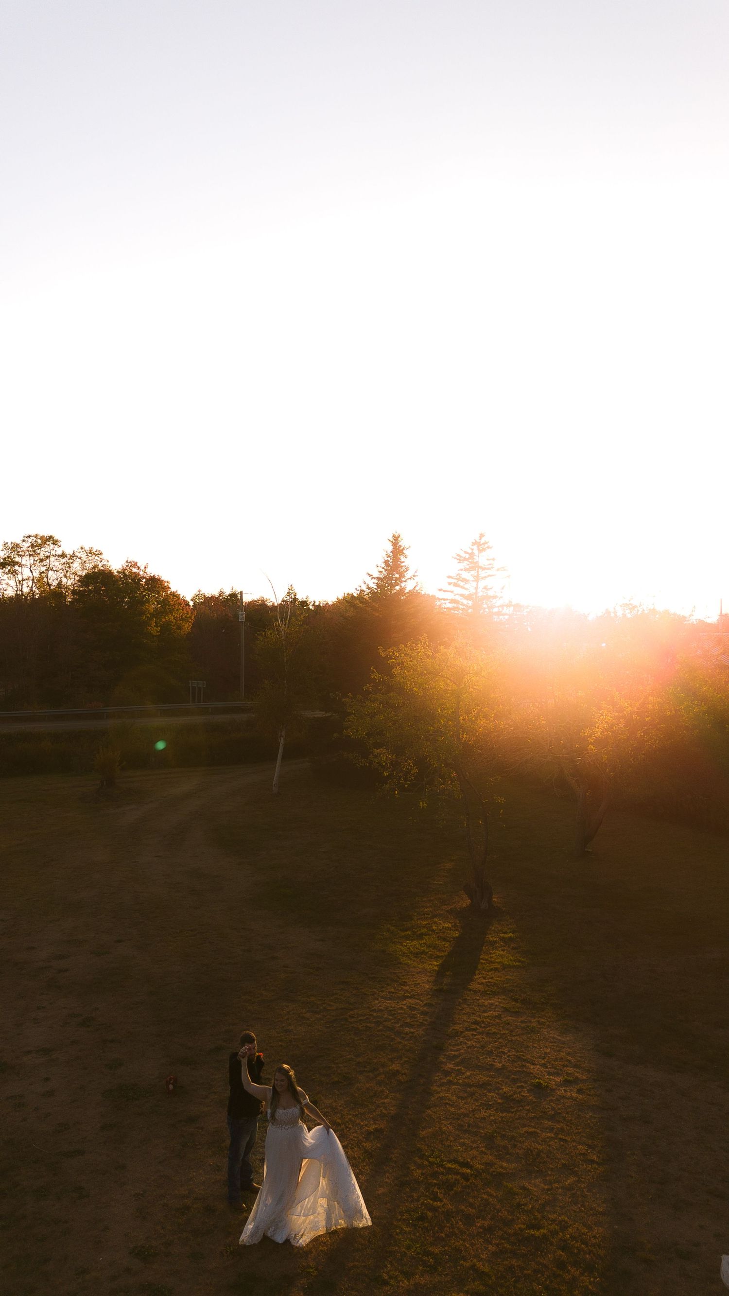 Silhouetted wedding couple dances in dramatic sunset lighting.
