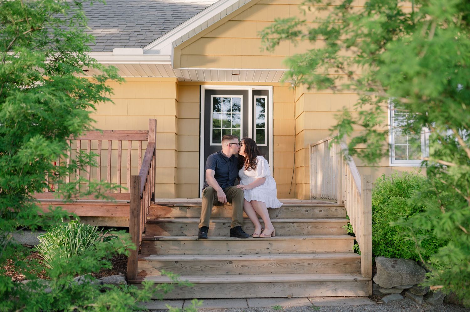 A rustic yellow building with wooden steps and a porch in a natural setting.