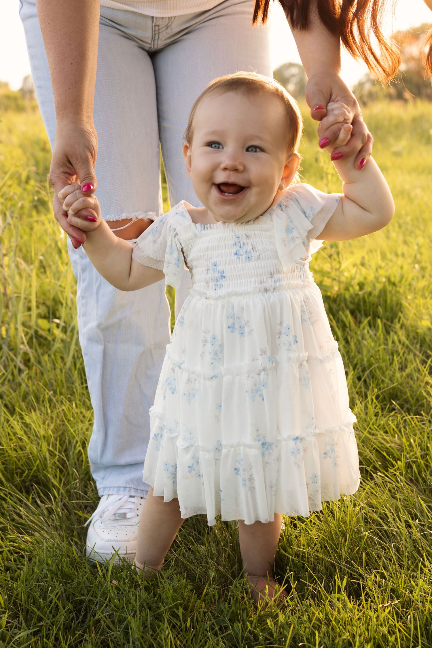 Mother holding her baby's hands as they walk together, capturing family moment in natural light for Sioux Falls family photography session