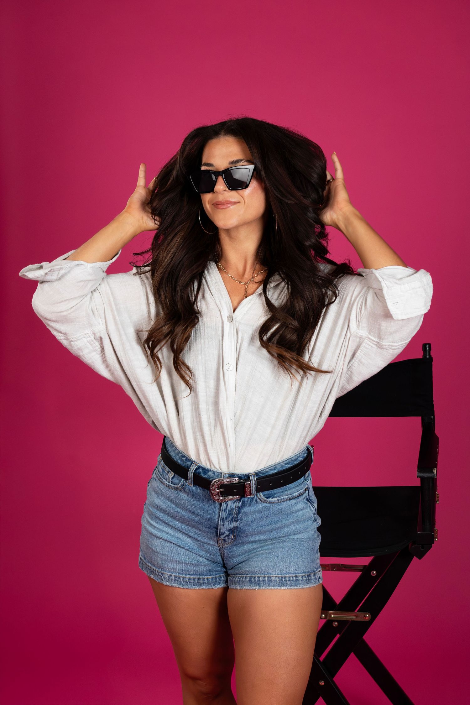 Professional hair stylist posing in a bright pink studio setting, showcasing creative branding and portrait photography in Sioux Falls, SD.